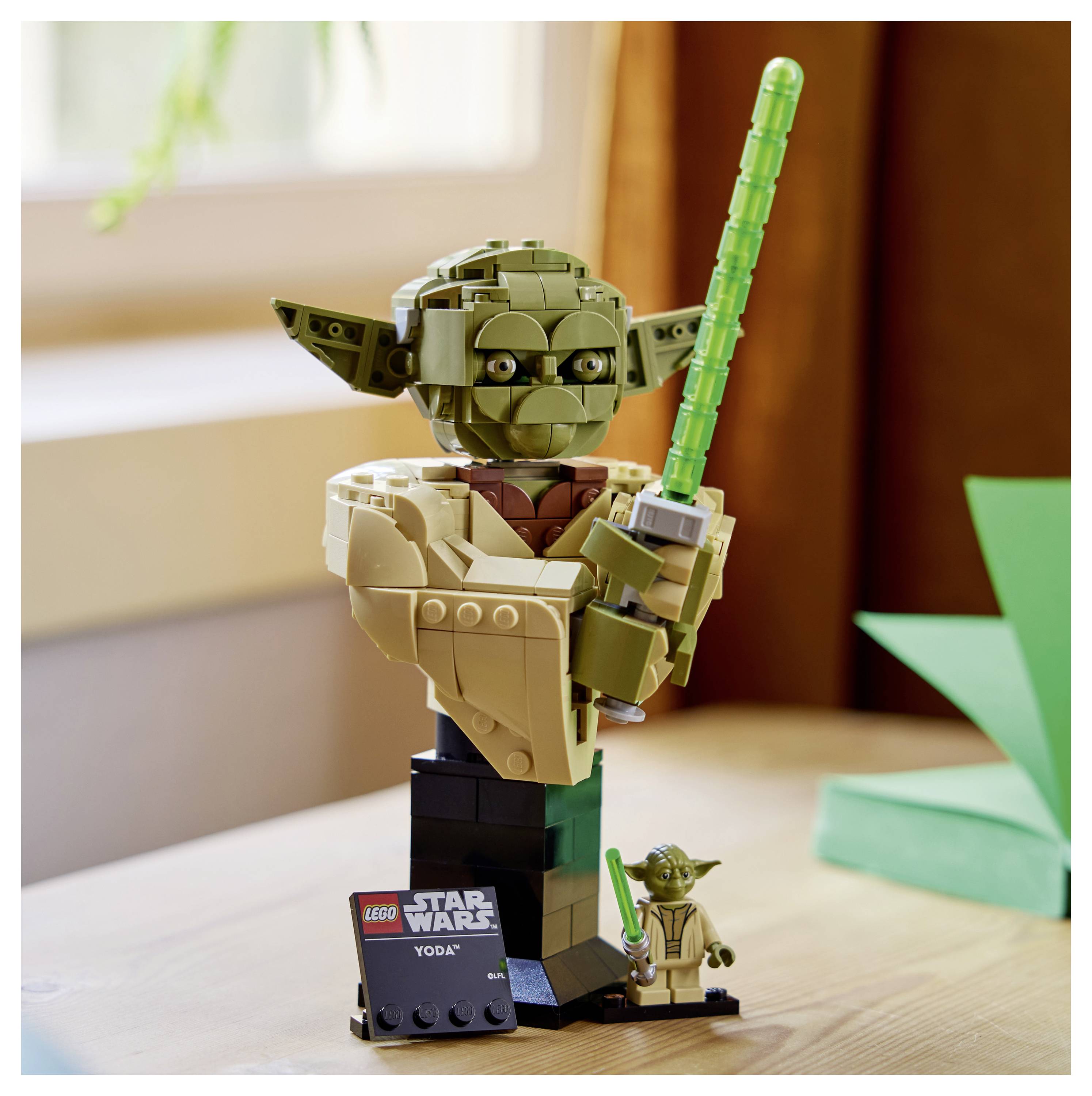 Ein LEGO-Modell von Yoda, der ein grünes Lichtschwert hält, mit einer kleinen Plakette, auf der „LEGO Star Wars Yoda