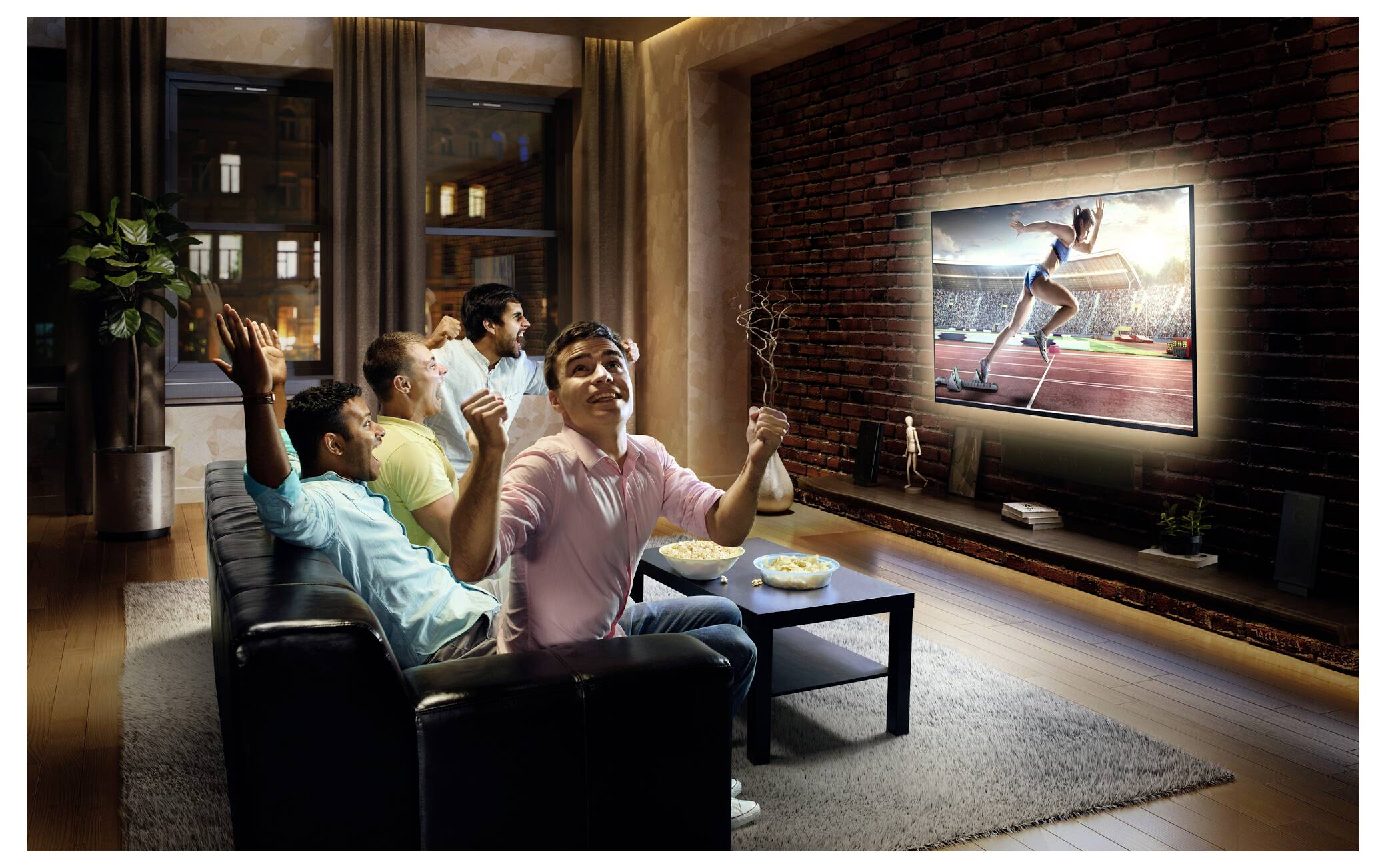 Eine Gruppe von fünf Personen sitzt auf einem Sofa und jubelt, während sie ein Sportereignis auf einem großen Fernseher in einer gemütlichen Wohnzimmeratmosphäre verfolgen.