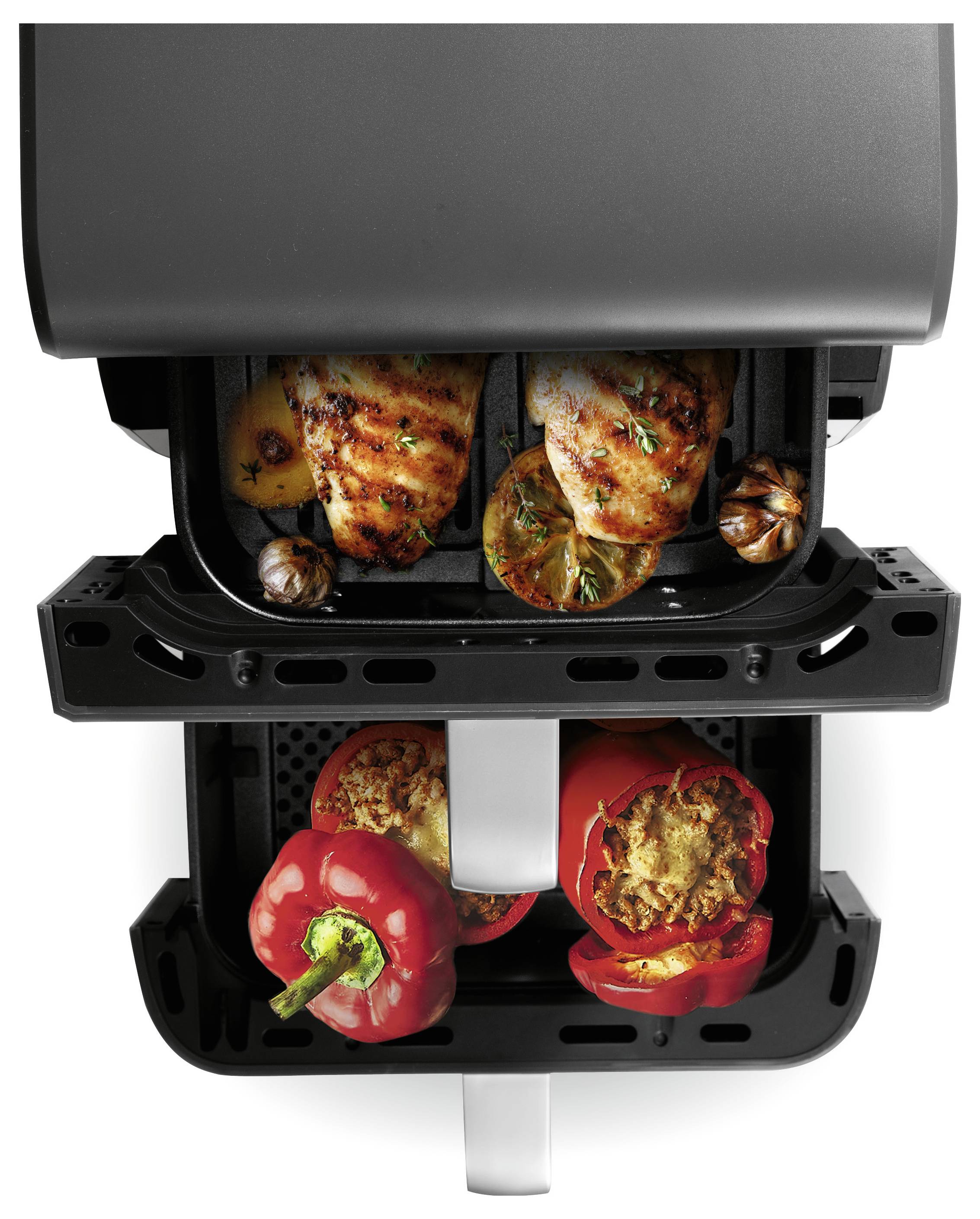 Dualer Heißluftfritteuse, der Hähnchenschenkel und Gemüse in einem Fach und gefüllte Paprikaschoten im anderen zubereitet, von oben betrachtet.
