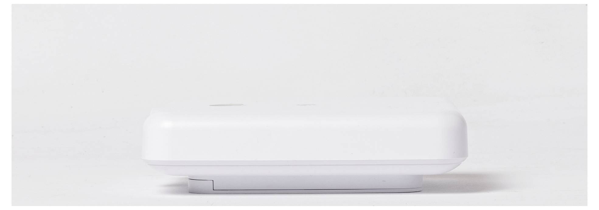 Ein weißes rechteckiges Objekt mit abgerundeten Kanten, von der Seite betrachtet, vor einem einfarbigen Hintergrund.