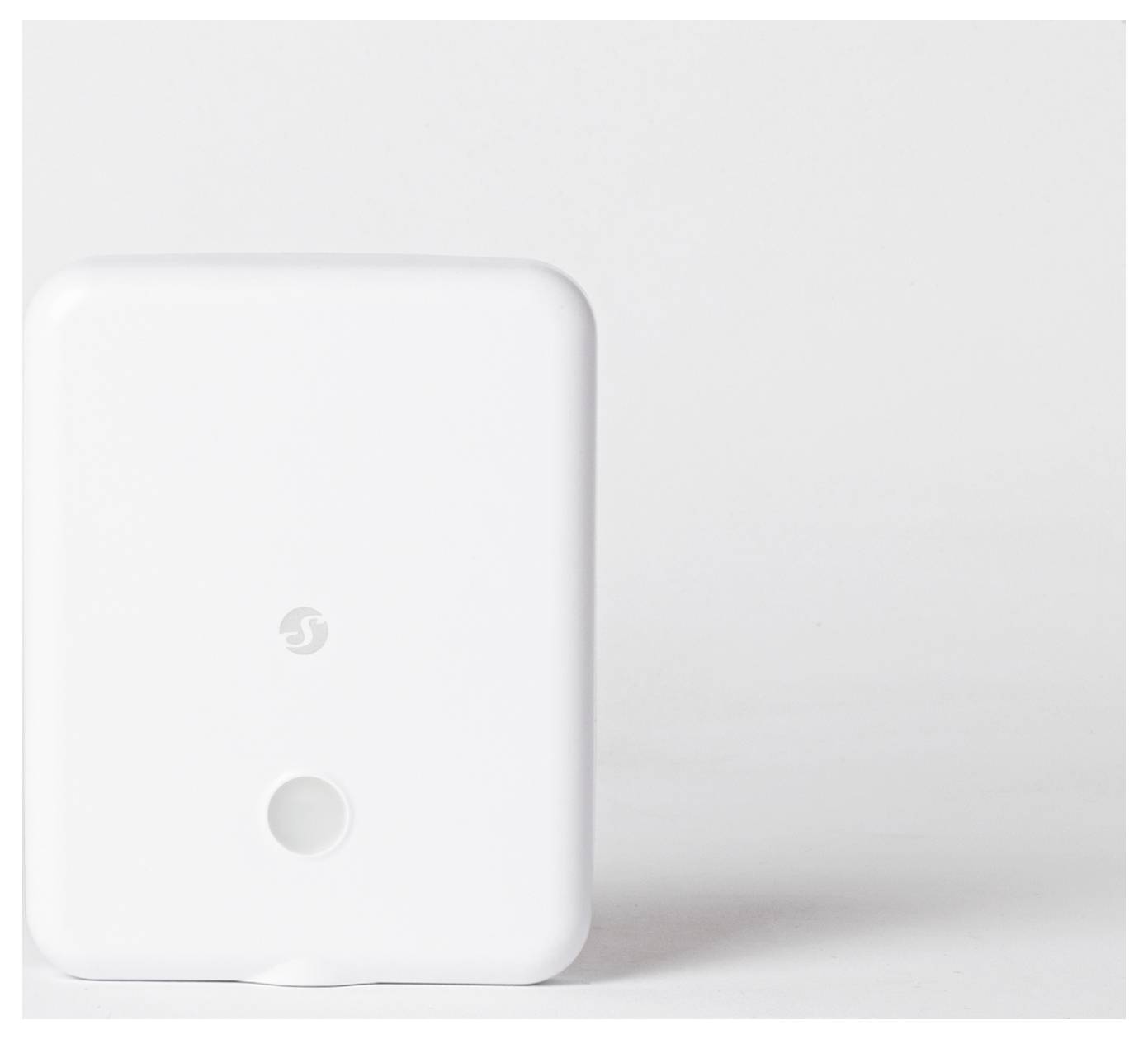 Weißes rechteckiges elektronisches Gerät mit einem kleinen Logo und einer kreisförmigen Öffnung auf der Vorderseite, gegen einen einfarbigen Hintergrund gelehnt.