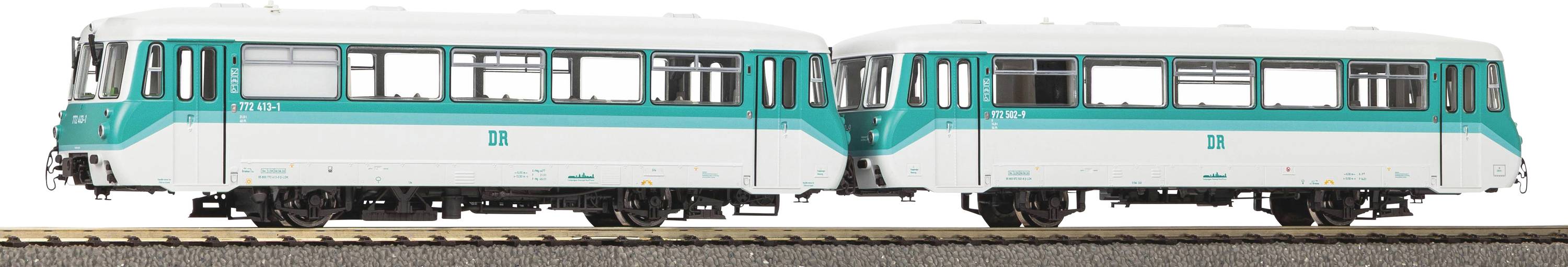 Ein Modelleisenbahn-Zug mit zwei verbundenen weiß-türkisen Wagen auf einer Schiene, mit detaillierten Fenstern und Rädern, vor weißem Hintergrund.