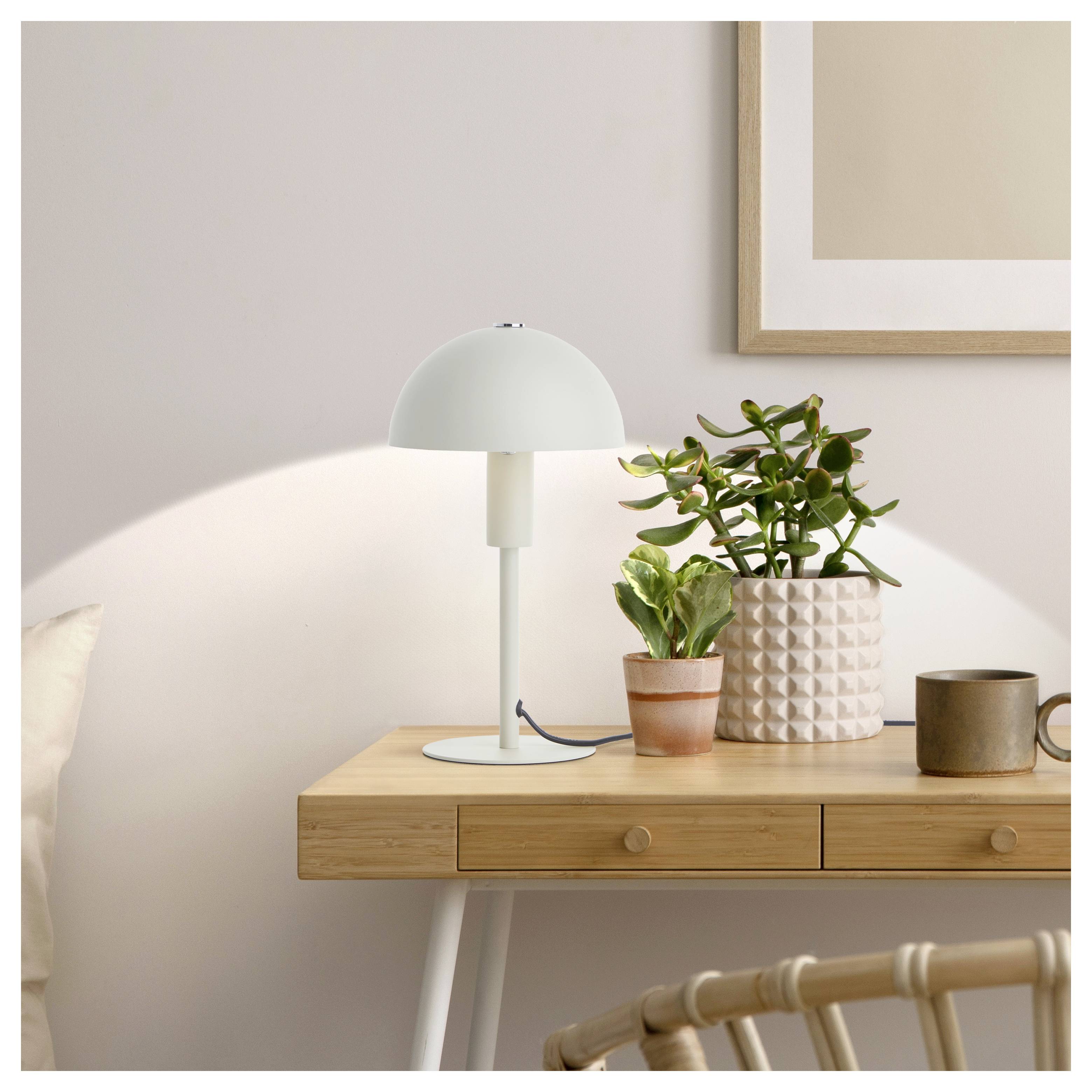 Ein minimalistischer Holzschreibtisch mit einer modernen weißen Lampe, Zimmerpflanzen und einem gerahmten abstrakten Kunstwerk an der Wand. Eine ruhige und gemütliche Einrichtung.