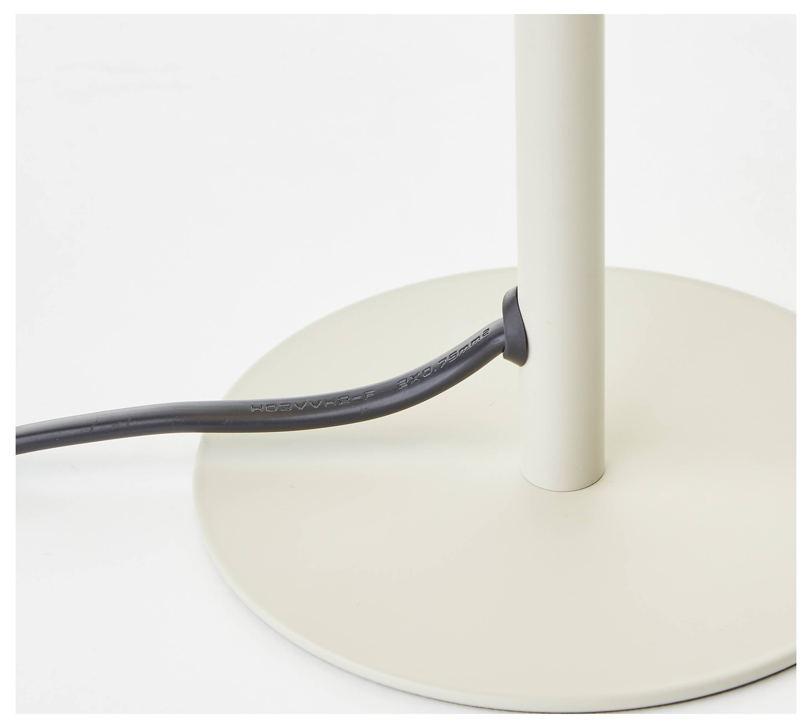 Eine beige Lampenhalterung mit einem schwarzen Netzkabel, von der Seite betrachtet.