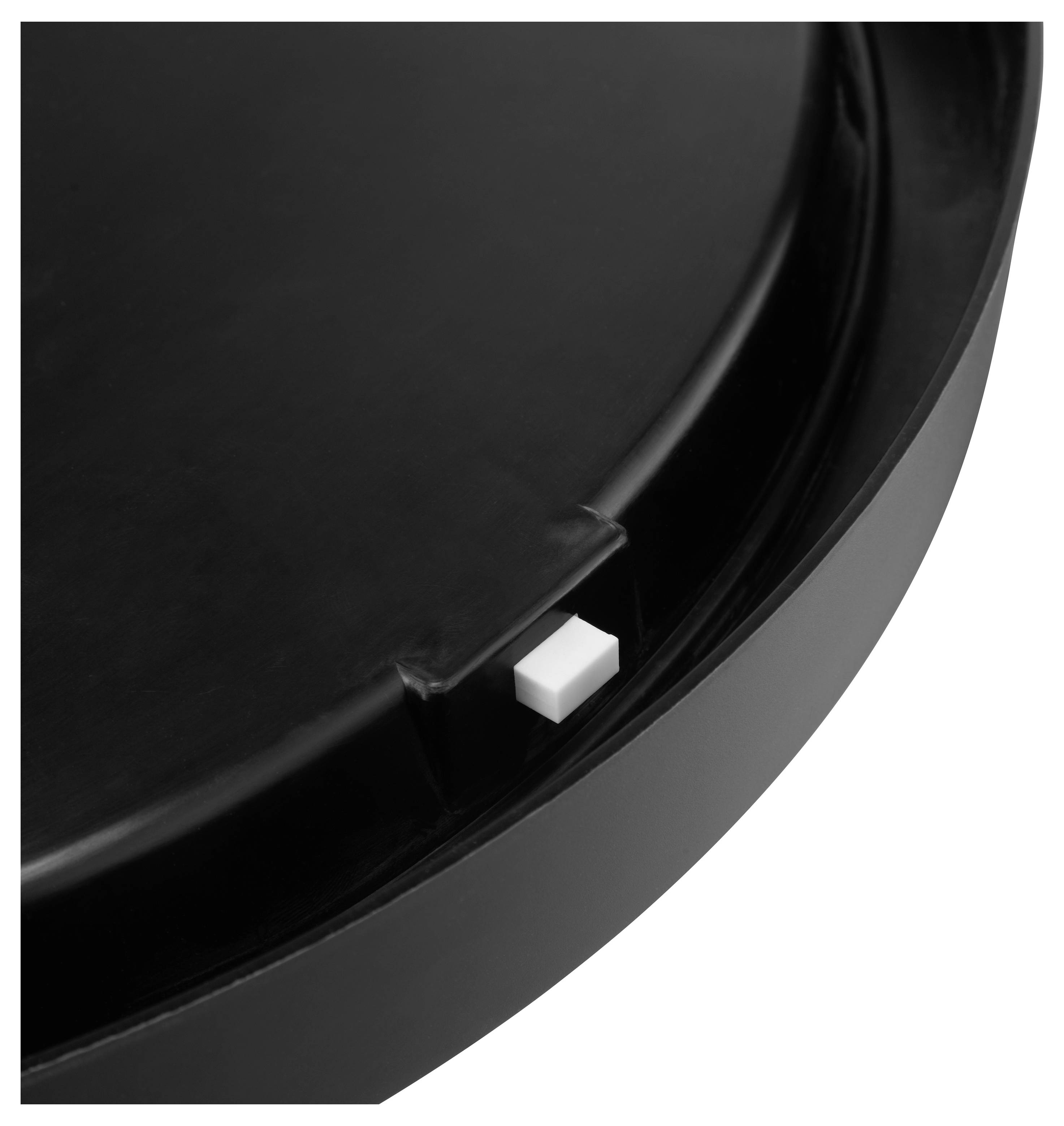 Ein schwarzes kreisförmiges Objekt mit einem kleinen weißen quadratischen Knopf, der seitlich eingelassen ist, möglicherweise ein Deckel oder eine Abdeckung mit einem Schalter.