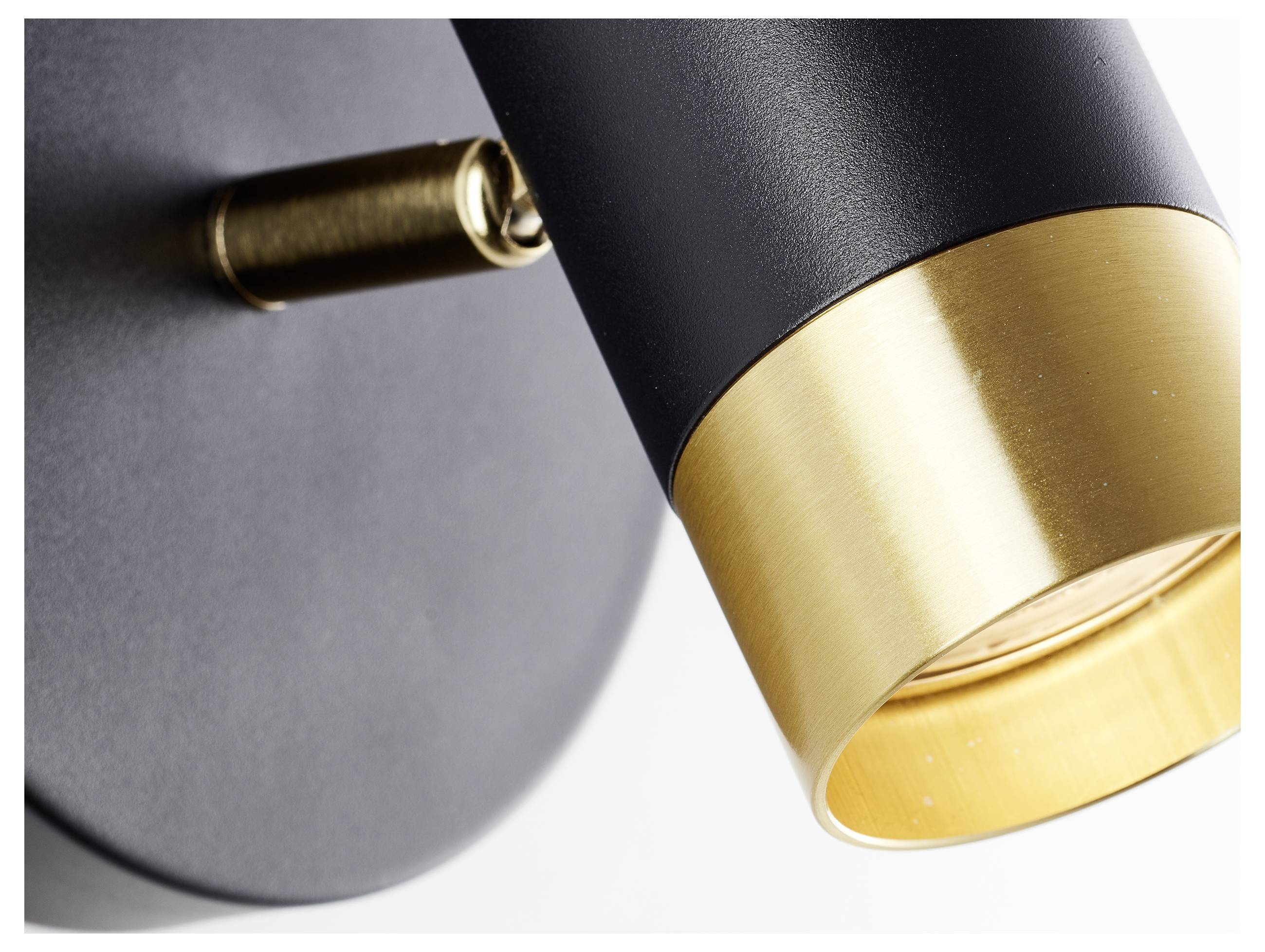 Nahaufnahme einer modernen Leuchte mit einem schwarzen zylindrischen Gehäuse und goldener Akzentuierung in der Nähe der Glühbirne.