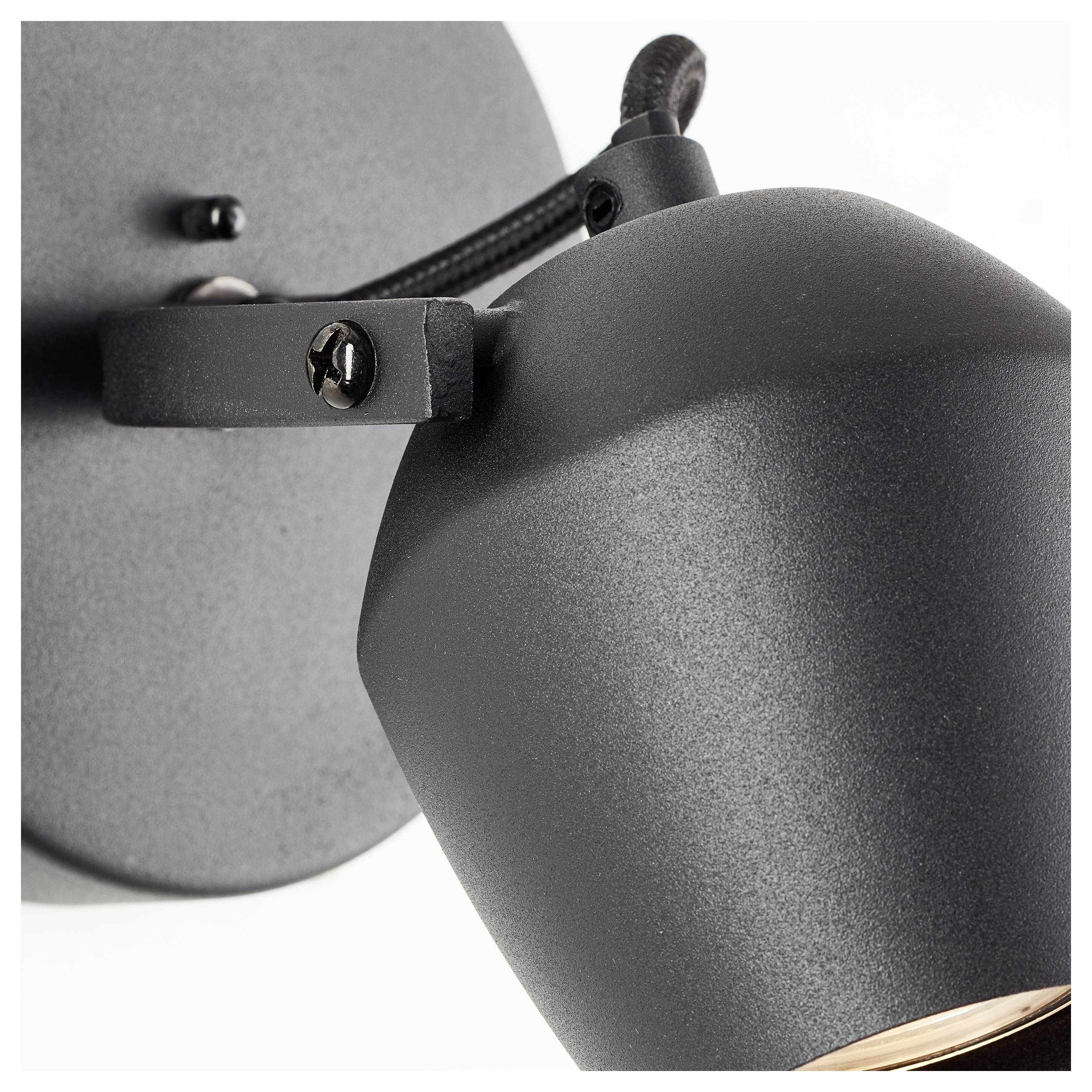 Nahaufnahme einer schwarzen Metallwandlampe mit glatter Oberfläche, die einen verstellbaren Lampenkopf besitzt und mit einer sichtbaren Schraube befestigt ist.