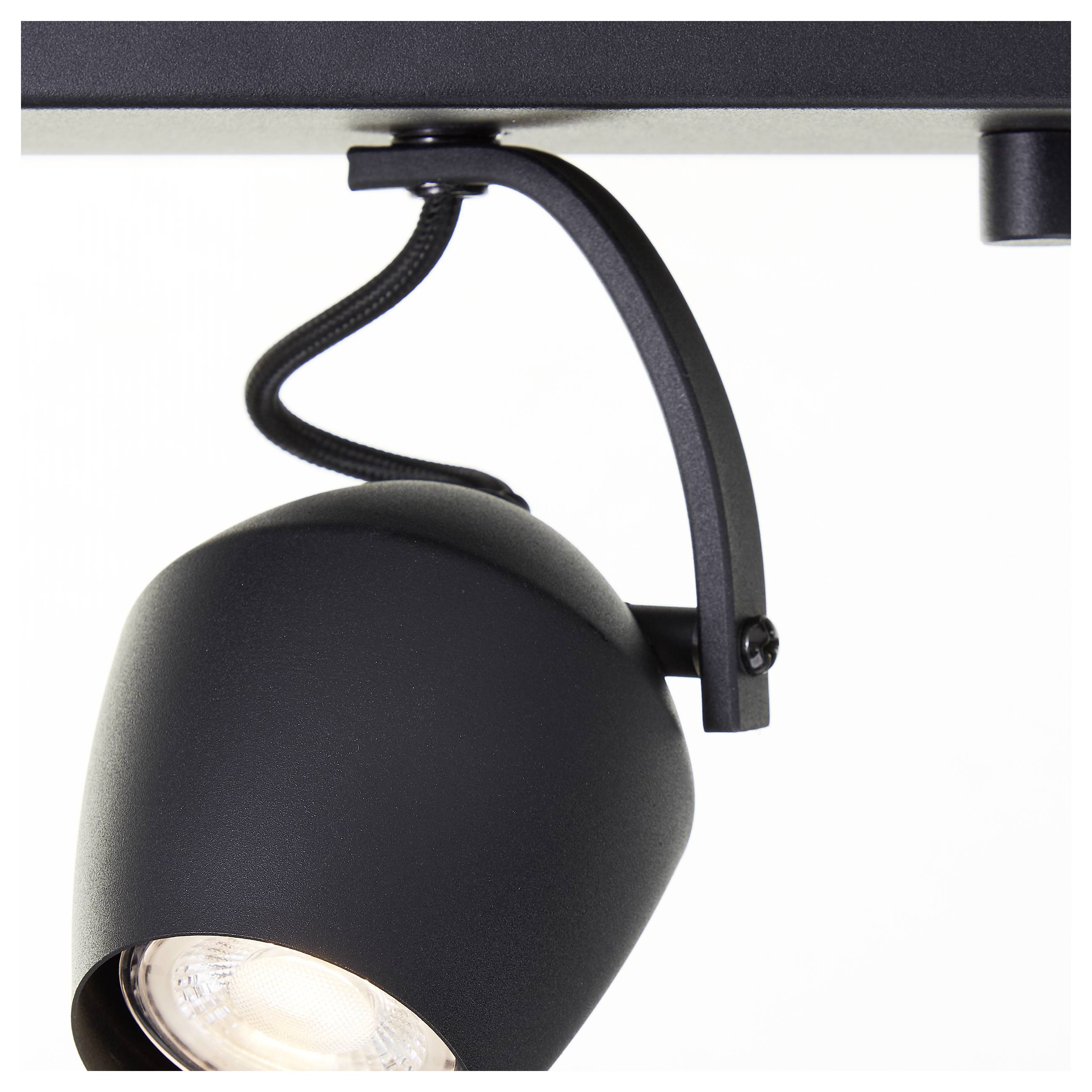 Eine schwarze Schienenbelechtungsarmatur, an der Decke montiert, mit einem verstellbaren Scheinwerfer, der nach unten gerichtet ist.
