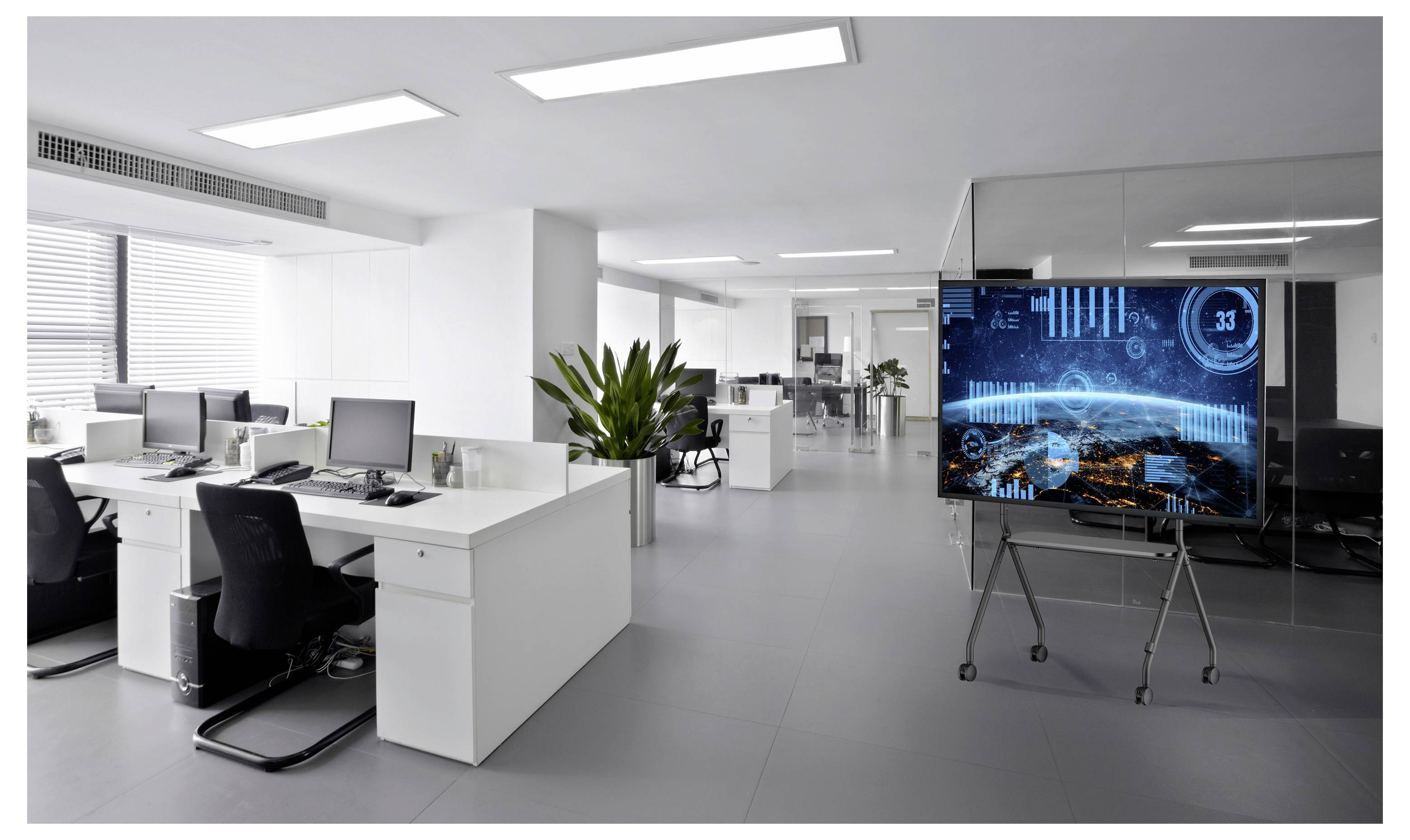 Modernes Open-Space-Büro mit weißen Schreibtischen und Computern sowie einem großen Bildschirm auf einem Ständer, der eine blaue digitale Daten-/Dashboard-Oberfläche anzeigt.