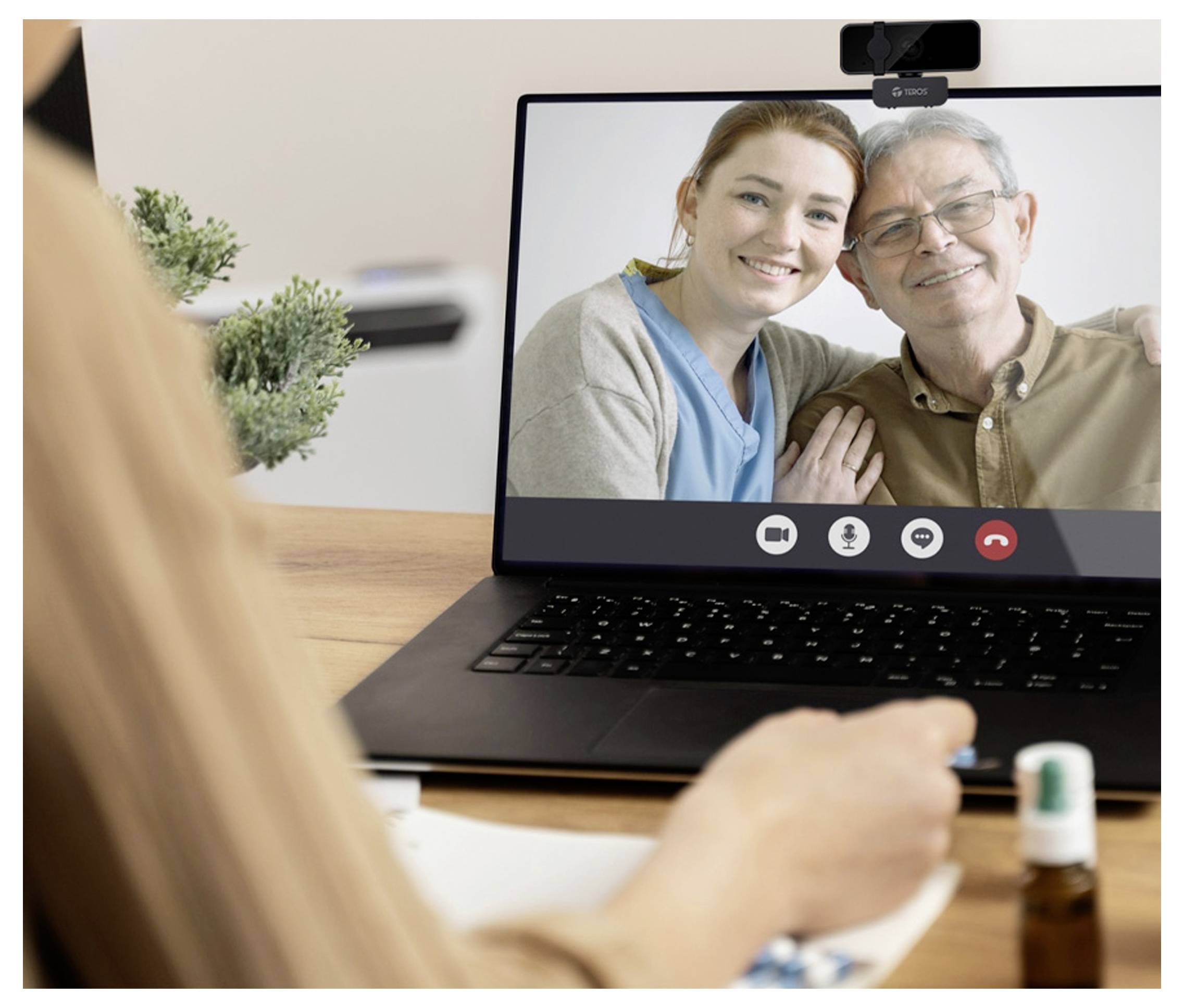 Eine Person nimmt an einem Videoanruf mit einem älteren Mann und einer Frau teil, die auf einem Laptop-Bildschirm angezeigt werden.