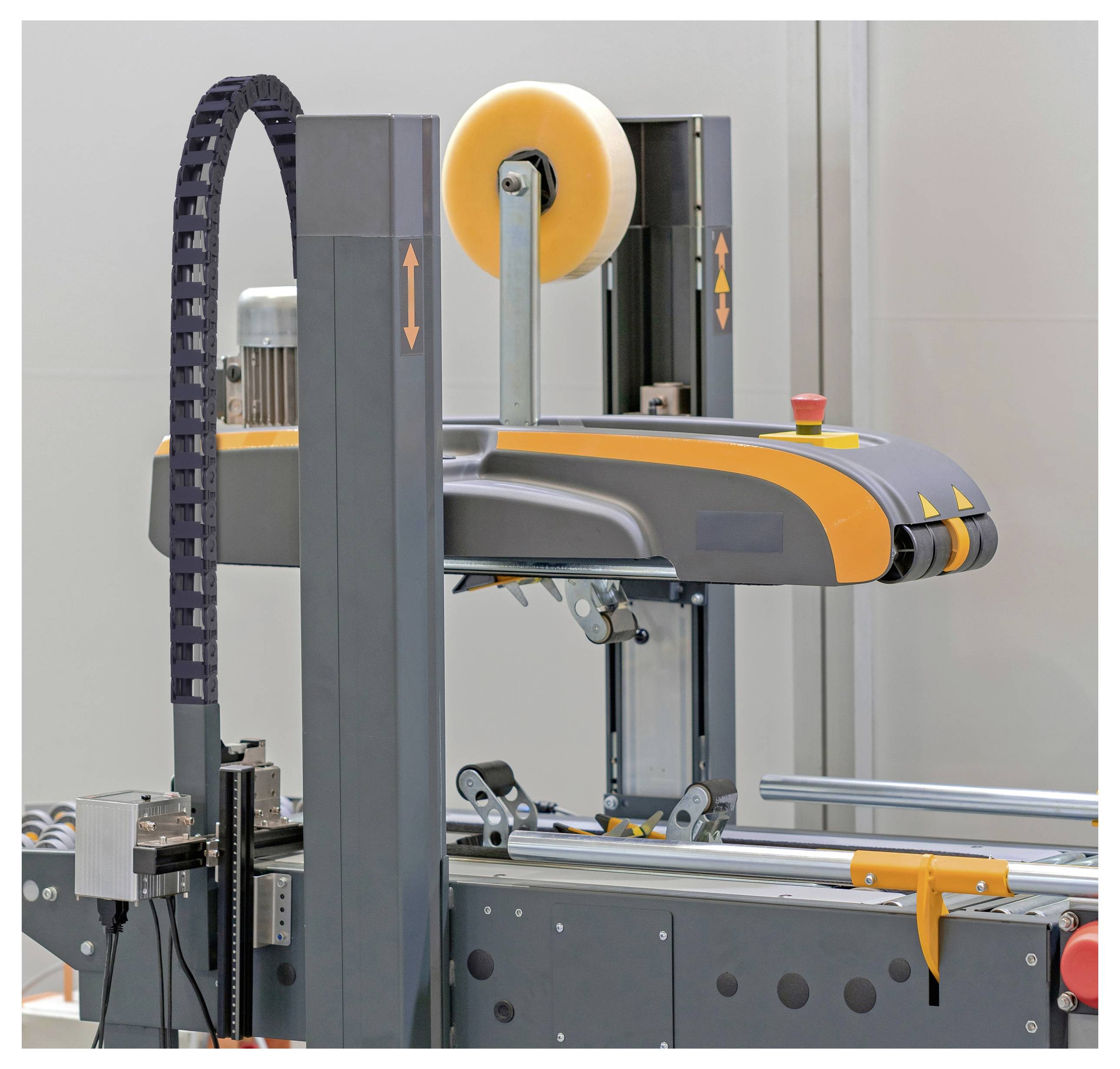 Eine automatisierte Verpackungsmaschine mit Förderbändern, Rollen und einem Klebeband-Spender, die zum effizienten Versiegeln und Bearbeiten von Kartons konzipiert ist.