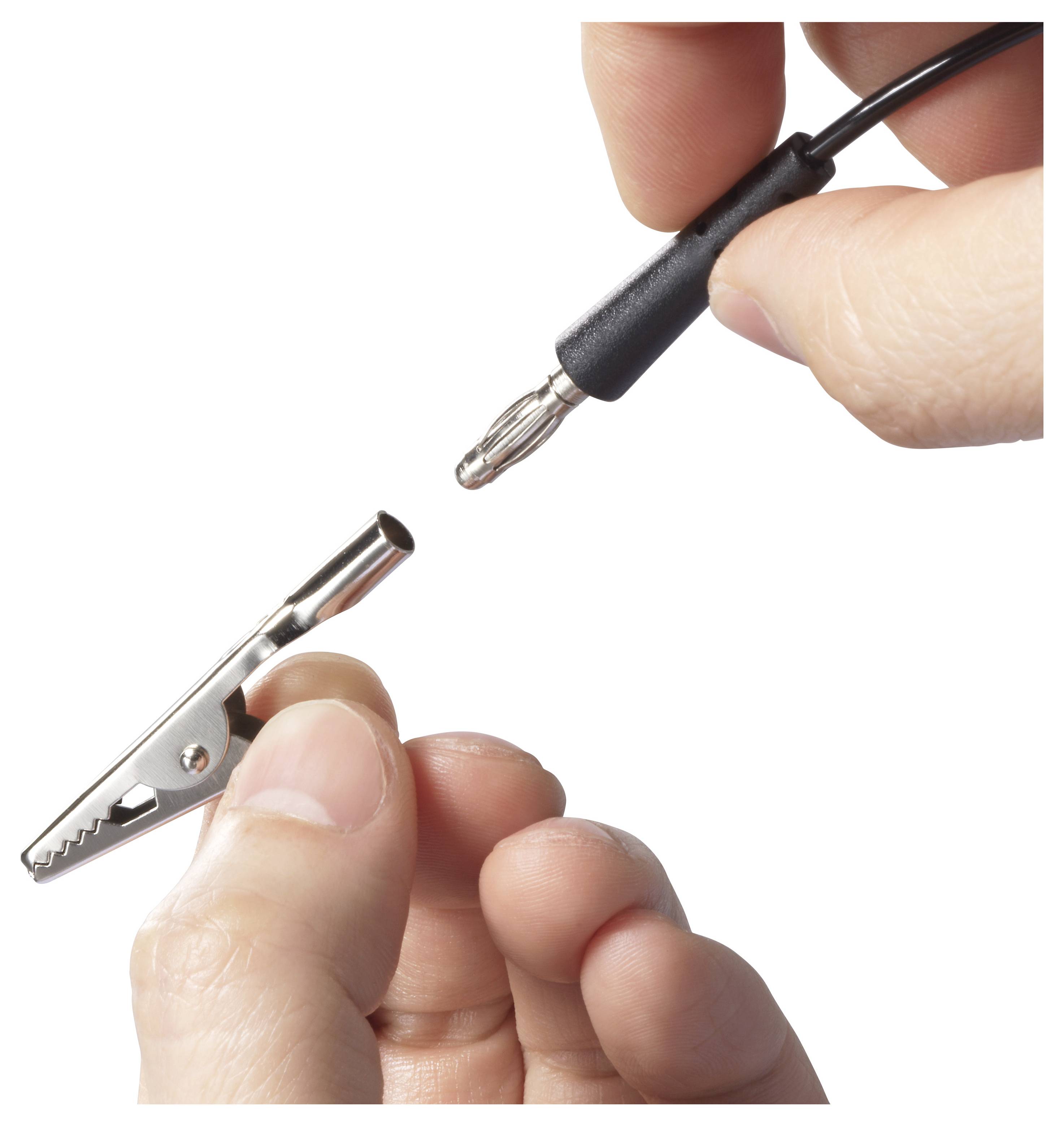 Eine Hand hält eine Krokodilklemme und eine andere Hand hält ein Messleitungskabel mit einer Bananenstecker, kurz davor, diese zu verbinden.
