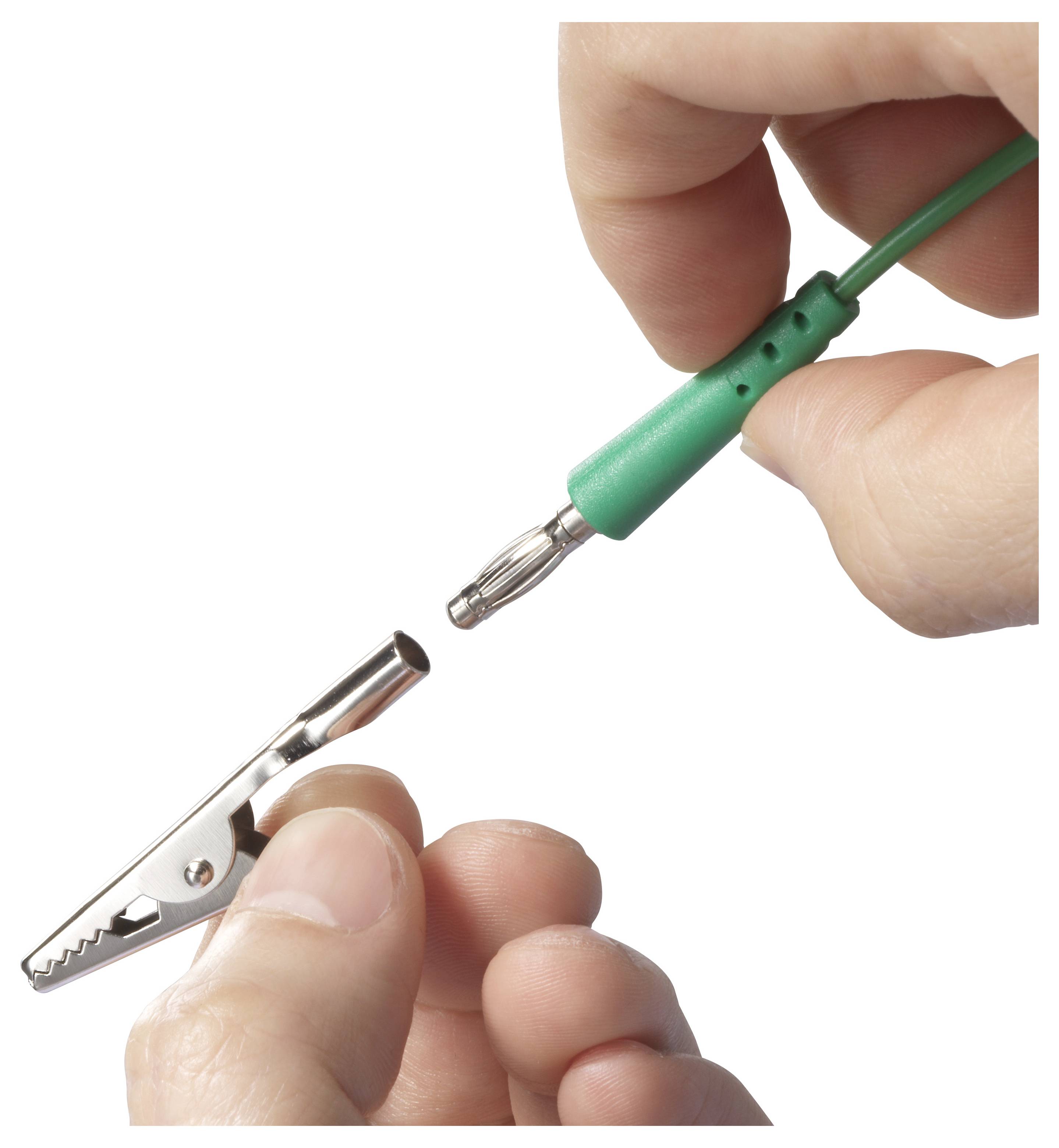Eine Person verbindet ein grünes Kabel mit einem Metallstecker mit einer Krokodilklemme, die von einer anderen Hand gehalten wird.