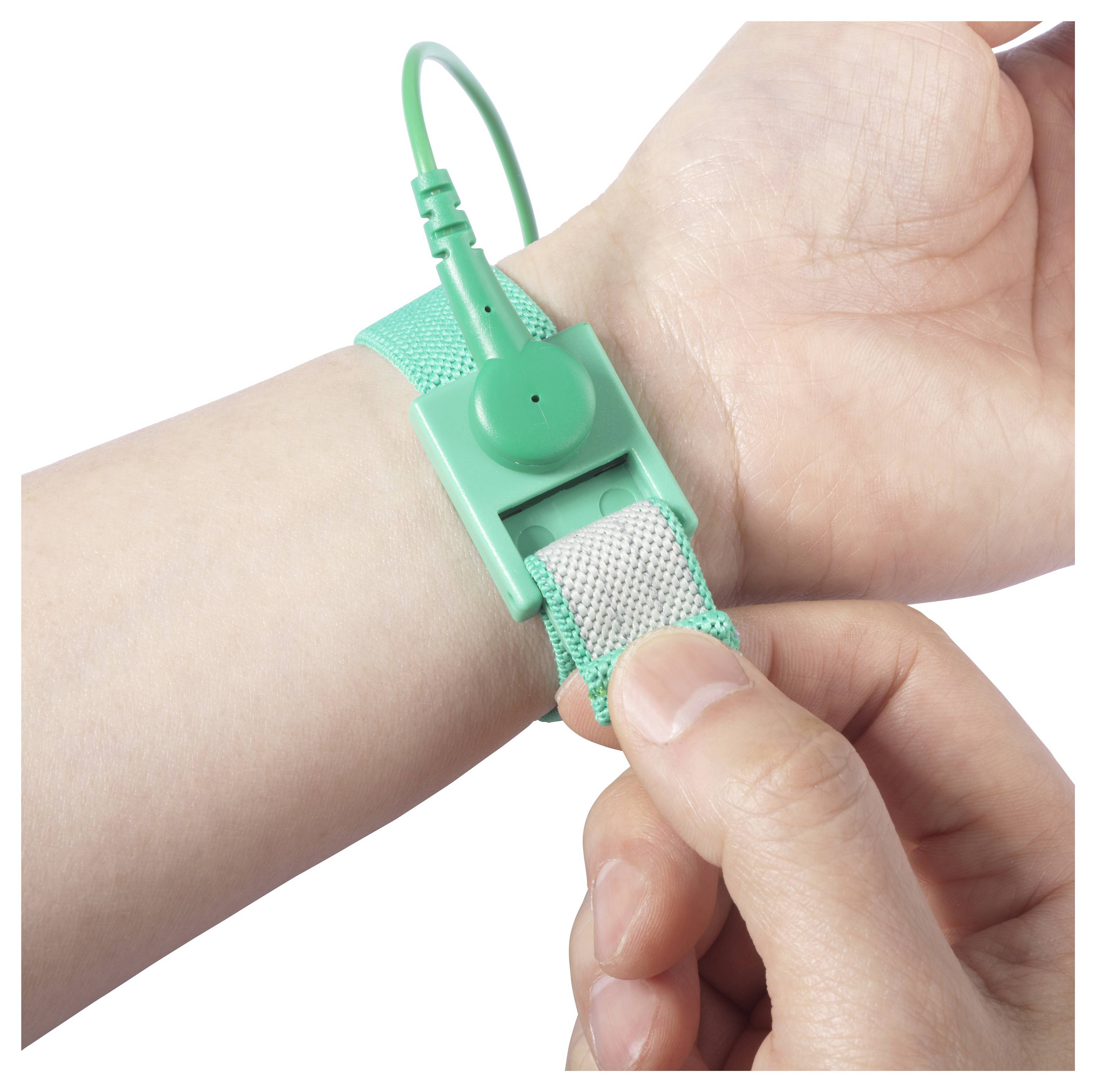 Eine Person, die ein grünes Armband, vermutlich ein antistatisches Armband, an ihrem Handgelenk anpasst, während sie mit der anderen Hand eine Schließe oder einen Stecker hält.