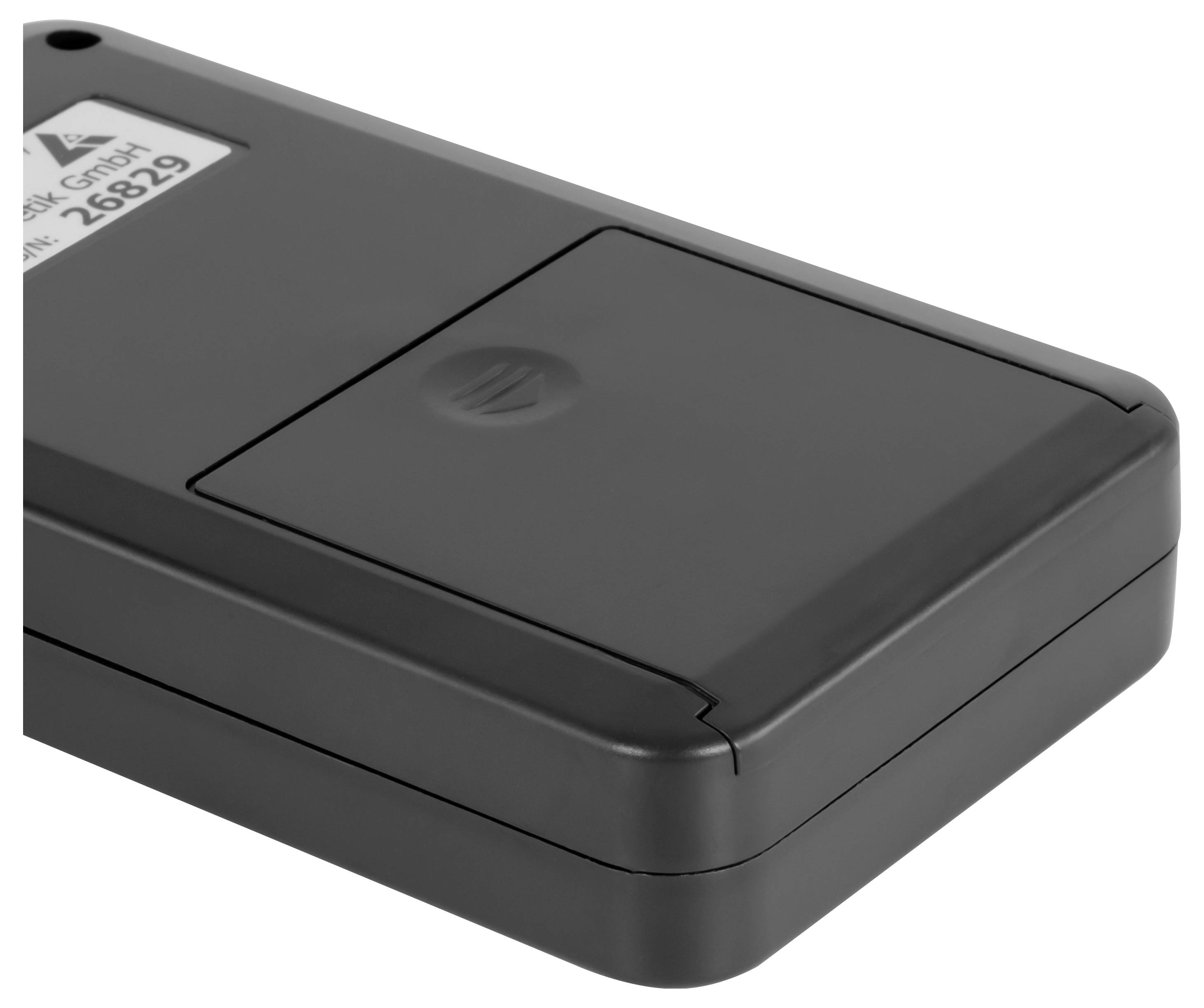 Schwarzes rechteckiges elektronisches Gerät oder Batteriepack mit kleinem Etikett und versenkt liegendem oberen Bedienfeld auf weißem Hintergrund