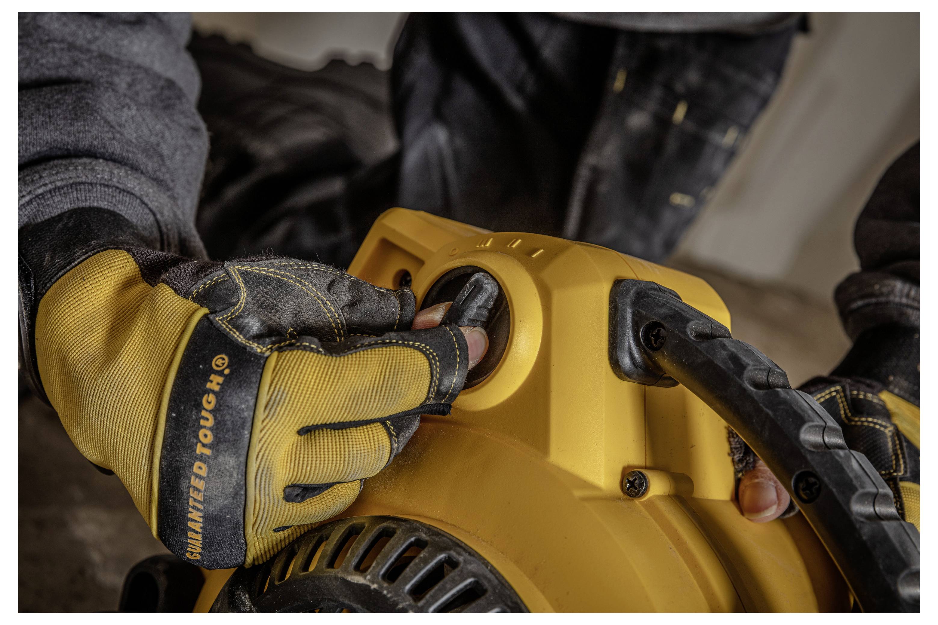 Behandschuhte Hände bedienen den Seilzugstarter an einer gelben tragbaren Maschine, wahrscheinlich einem Generator oder einer Hochdruckreiniger.