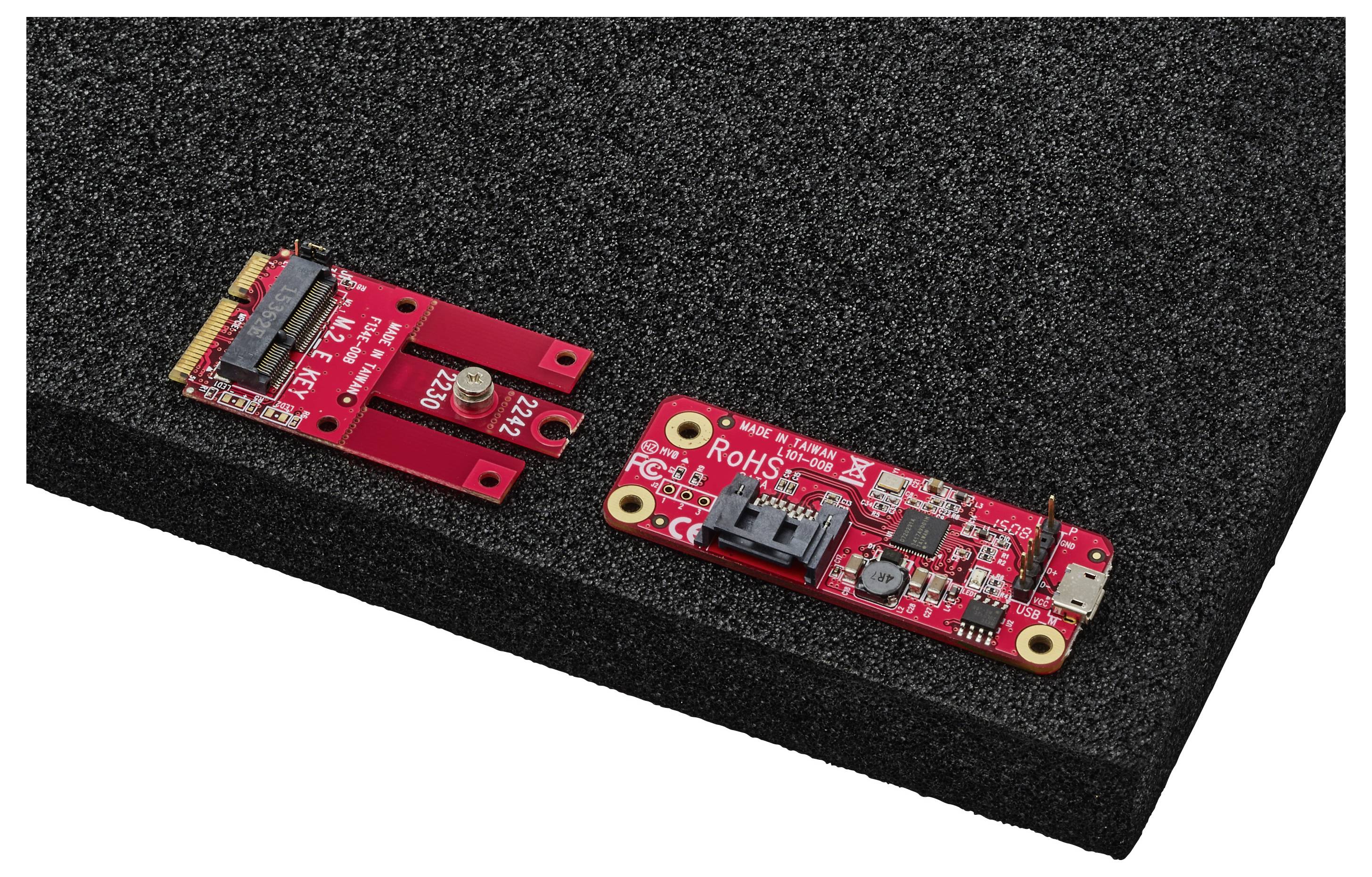 Zwei rote elektronische Leiterplatten auf einer schwarzen Schaumstoffoberfläche, die verschiedene Steckverbinder und elektronische Komponenten aufweisen.