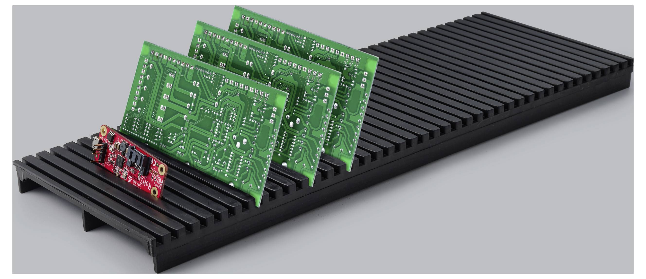 Drei grüne Leiterplatten und eine kleine rote Platine, die in Schlitzen auf einer schwarzen Grundplatte mit Schlitzen montiert sind, dargestellt als Elektronik-Baugruppe oder Anzeigeständer.