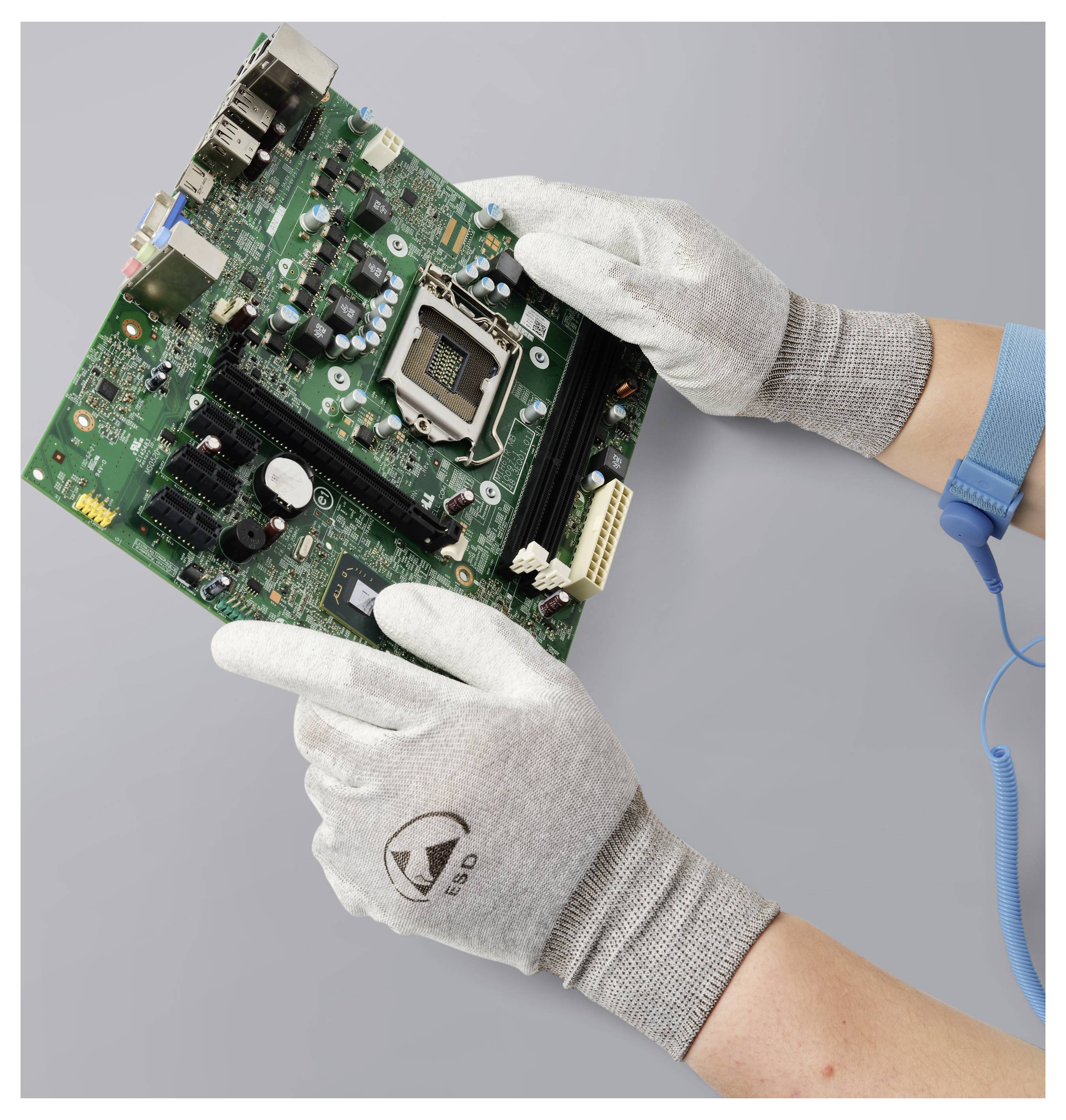 Hände mit antistatischen Handschuhen handhaben eine Computerplatine vor grauem Hintergrund und betonen sorgfältige Elektronikbehandlung.