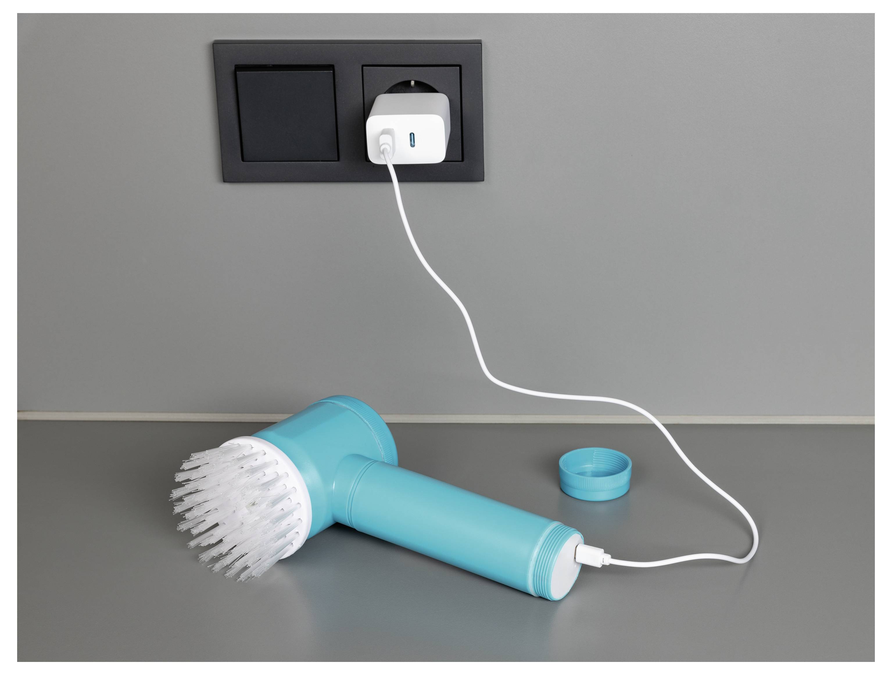 Eine Person benutzt einen Staubsaugerschlauch, um einen roten Flüssigkeitsfleck von einem weißen Teppich zu entfernen, wobei ein Teil eines grauen Sofas im Hintergrund sichtbar ist.