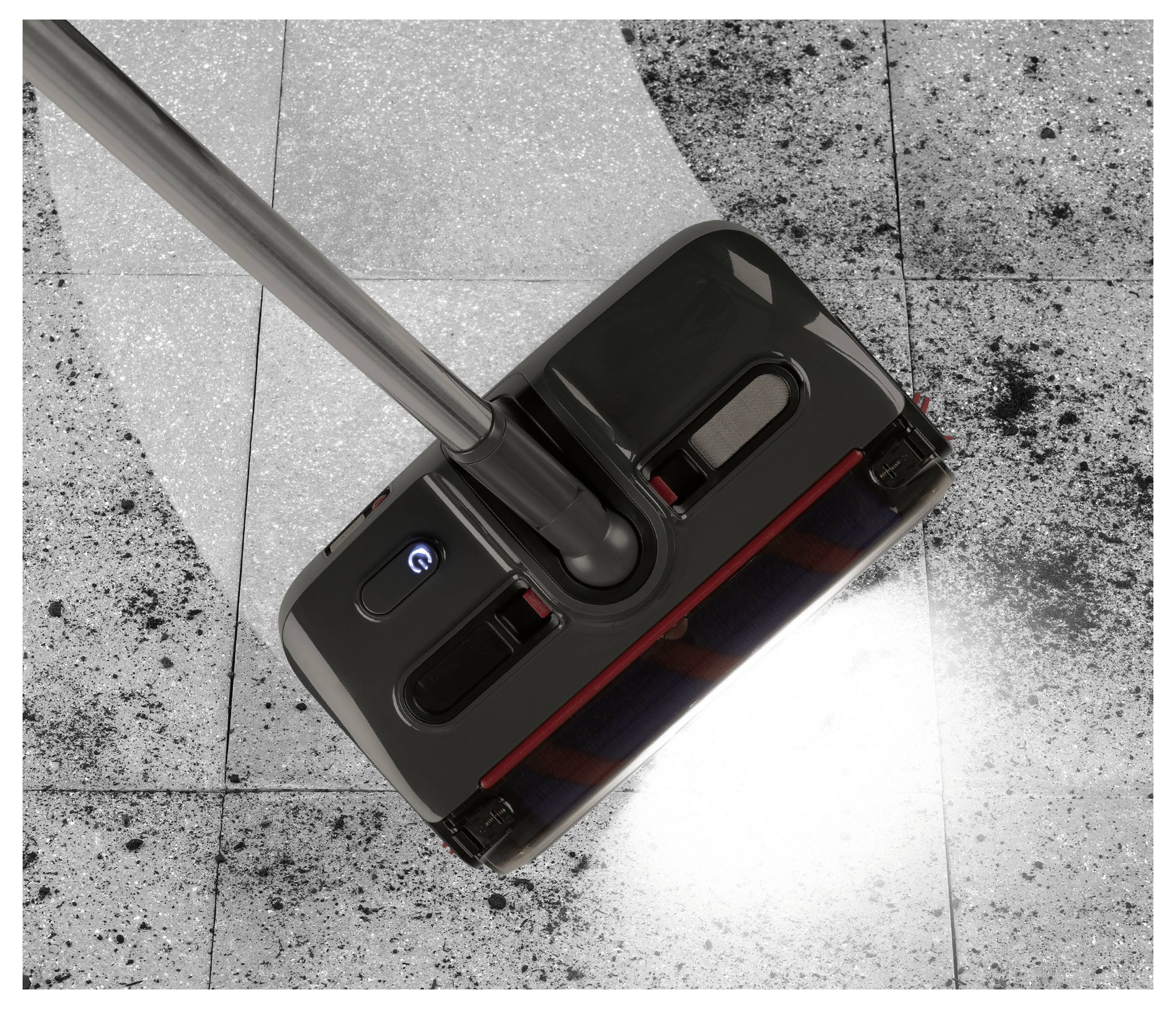 Eine Bodenreinigungsmaschine in Gebrauch, die Staub und Schmutz von einem Fliesenboden kehrt und einen sauberen Weg hinter sich lässt.