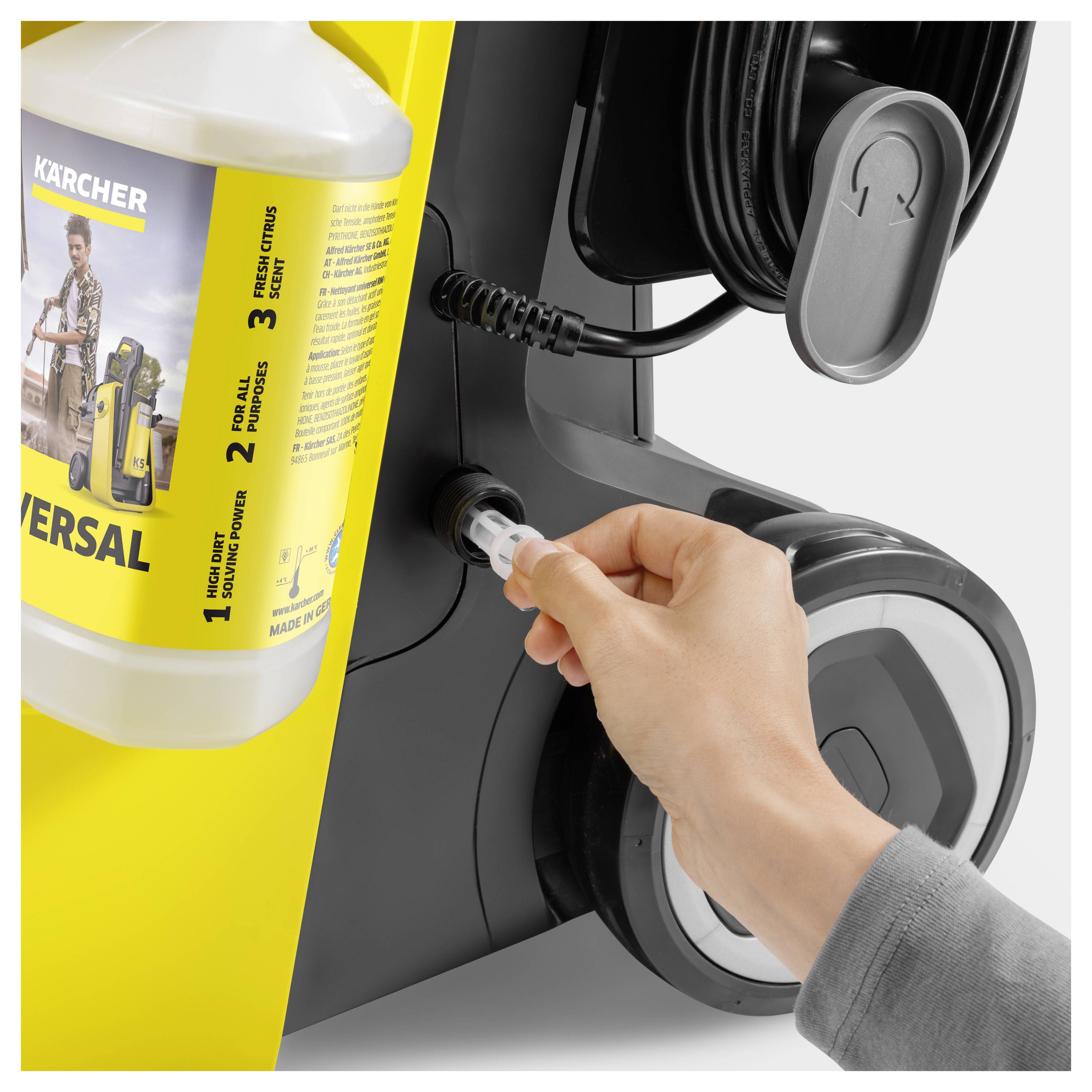 Eine Person, die einen Waschmittelcontainer in ein Reinigungsgerät einsetzt, mit Fokus auf die Verbindungsstelle. Das Gerät ist schwarz und gelb.