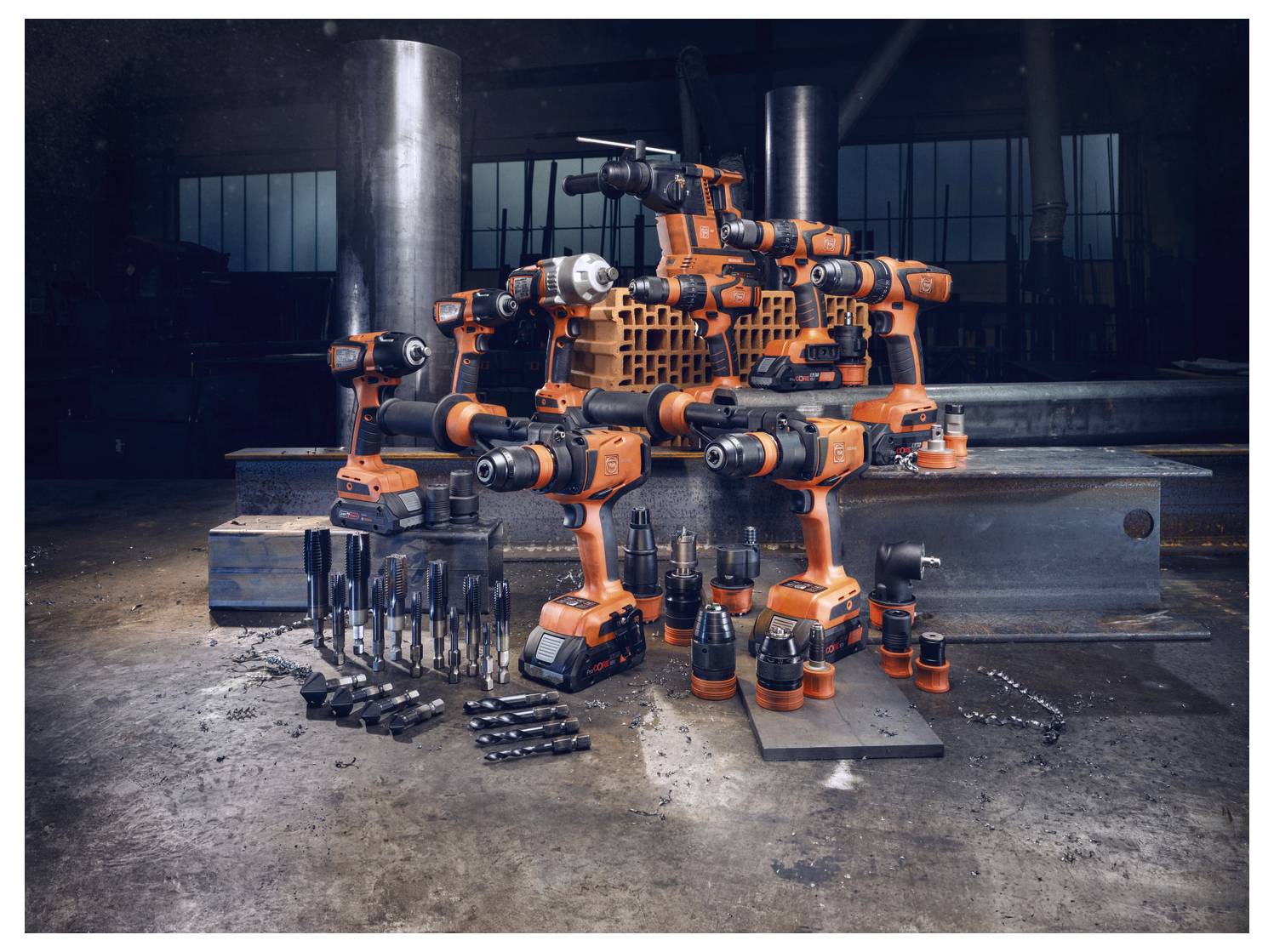 Eine Sammlung aus orangefarbenen und schwarzen Elektrowerkzeugen ist kreativ arrangiert, um einen Roboter in einer Industrieumgebung mit Stahlträgern zu ähneln.
