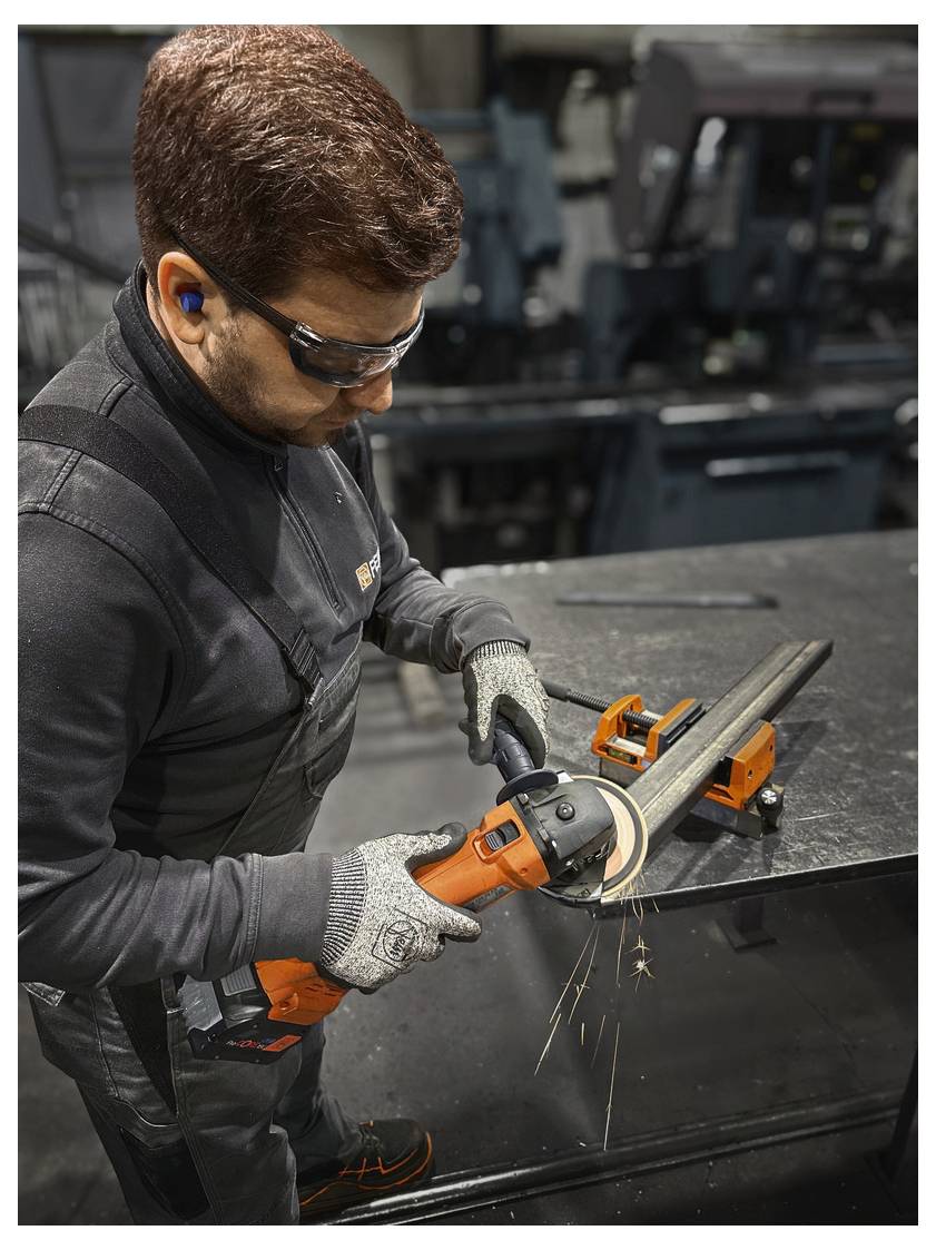 Ein Arbeiter in Schutzausrüstung benutzt einen Winkelschleiffer an einem Metallrohr in einer industriellen Umgebung, wobei Funken vom Werkzeug fliegen.