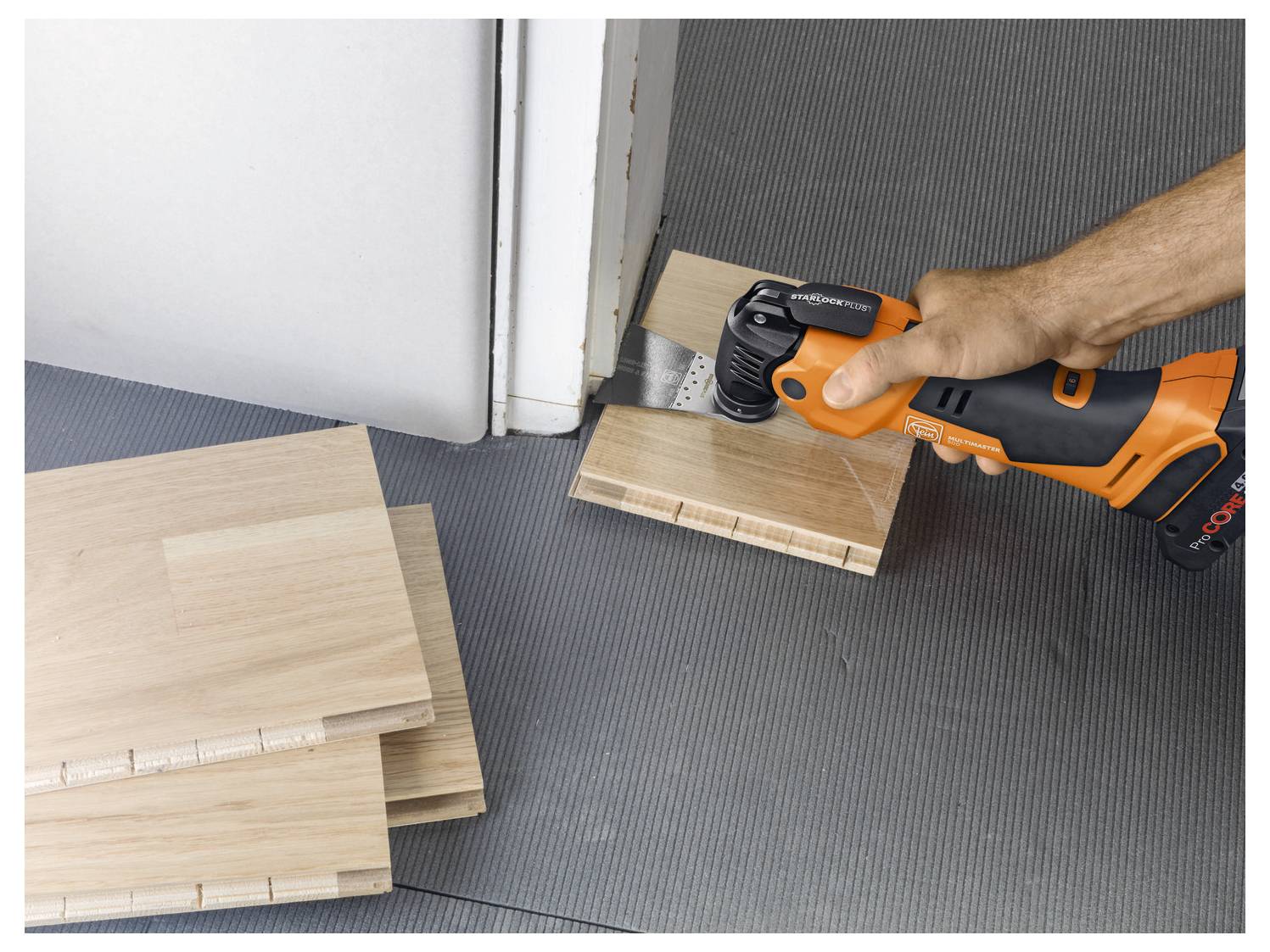 Eine Person verwendet eine elektrische Säge, um Holzplatten in der Nähe einer Türöffnung zu schneiden und bereitet sich auf die Bodenverlegung vor.