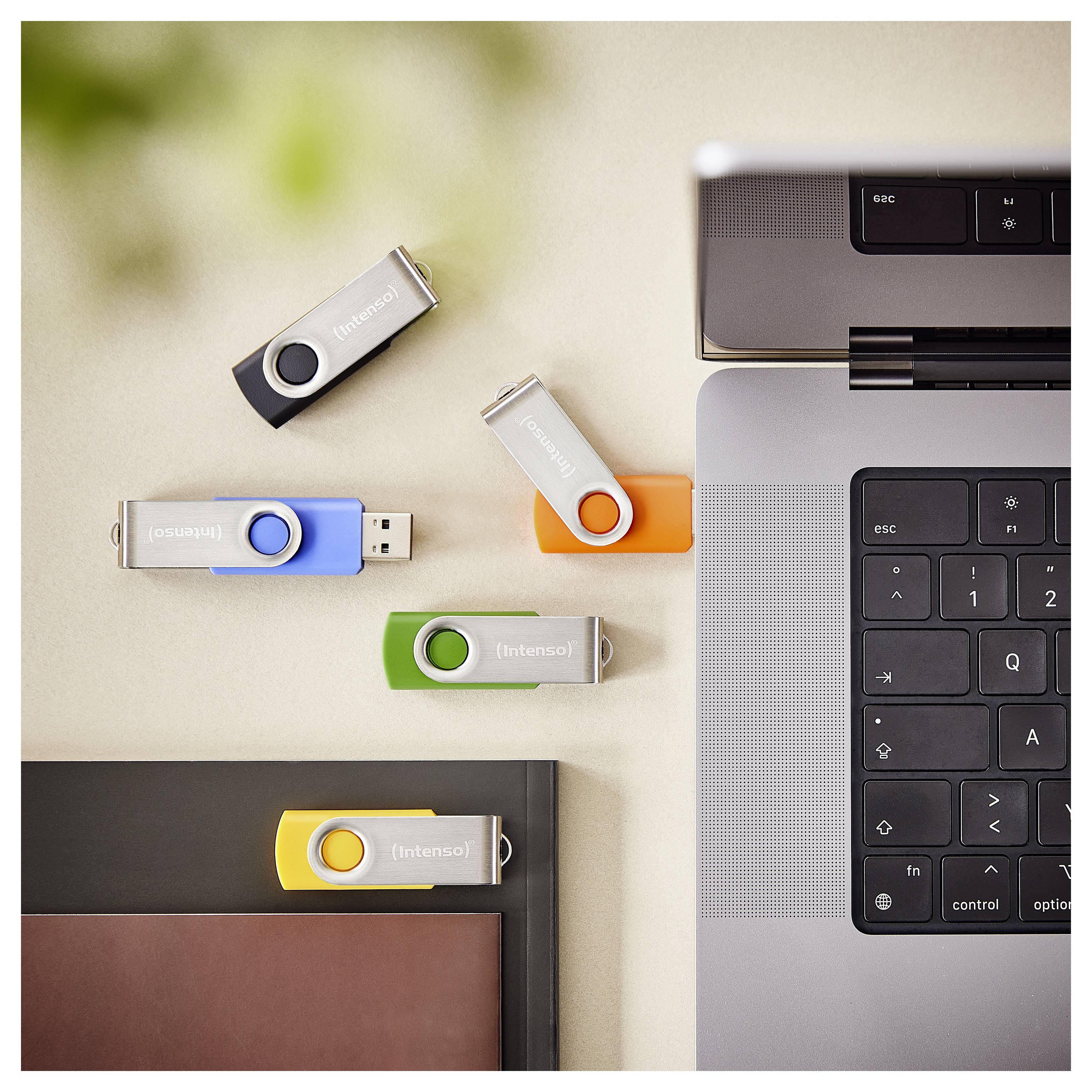 Ein Laptop auf einem Schreibtisch mit fünf USB-Laufwerken in verschiedenen Farben, die Datenübertragung oder Speicheroptionen andeuten.