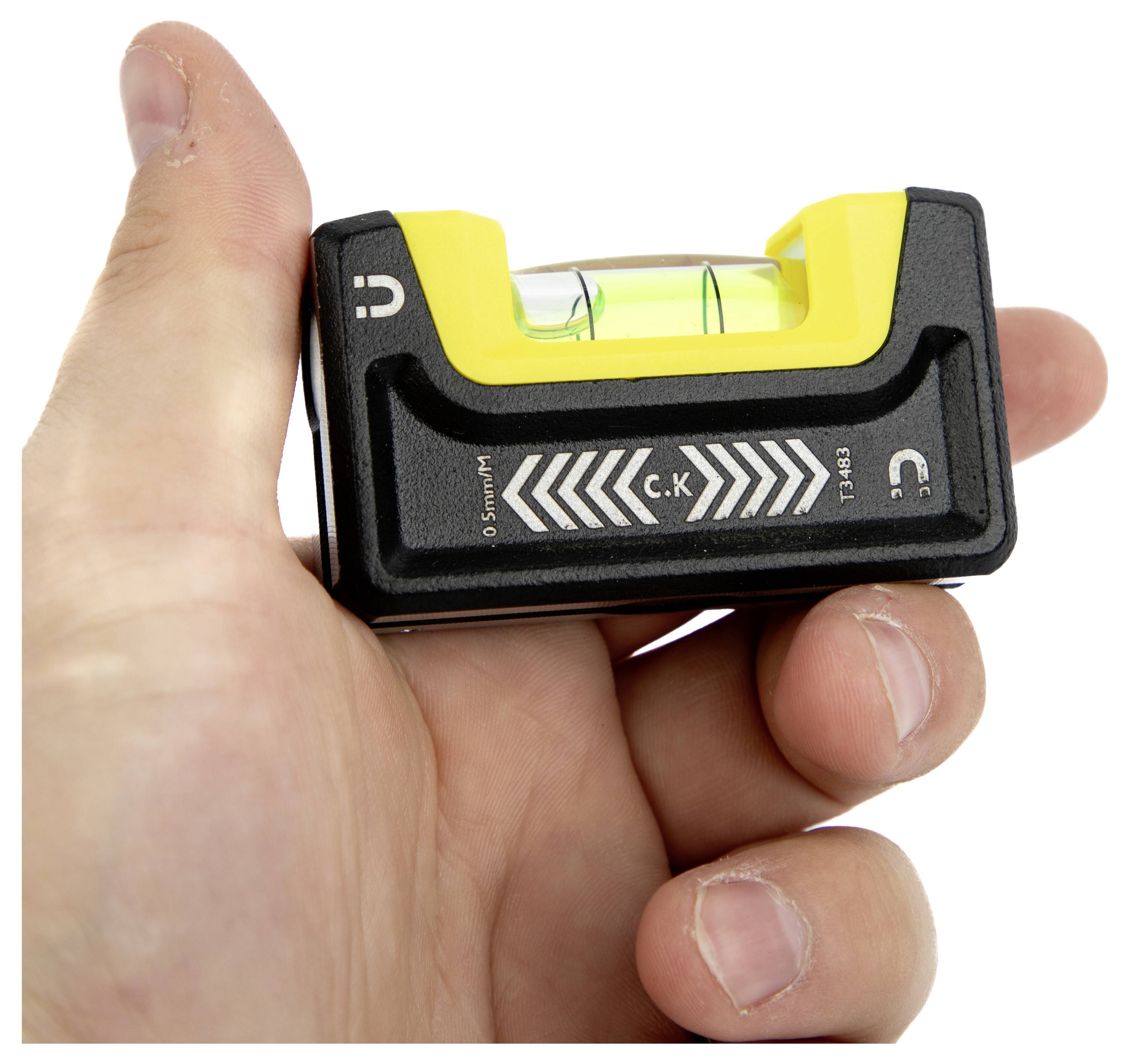 Eine Hand hält ein kleines, gelb-schwarzes Wasserwaagenwerkzeug mit einer sichtbaren Blase in der flüssigkeitsgefüllten Röhre zur Messung der horizontalen Ausrichtung.