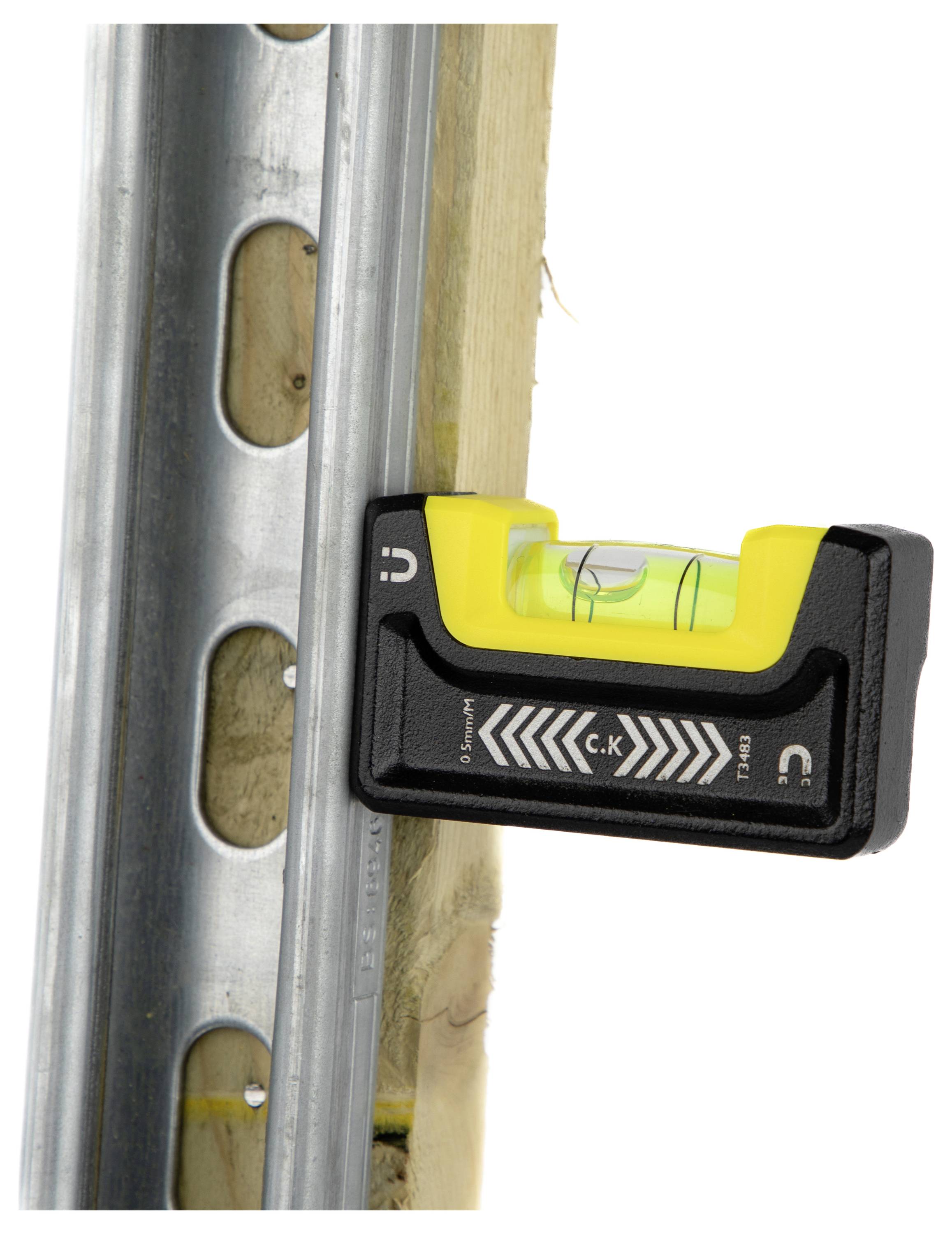 Eine kleine Wasserwaage, die magnetisch an einem Stahlträger befestigt ist, zeigt eine zentrierte Blase an, was darauf hindeutet, dass der Träger vertikal ebenen ist.