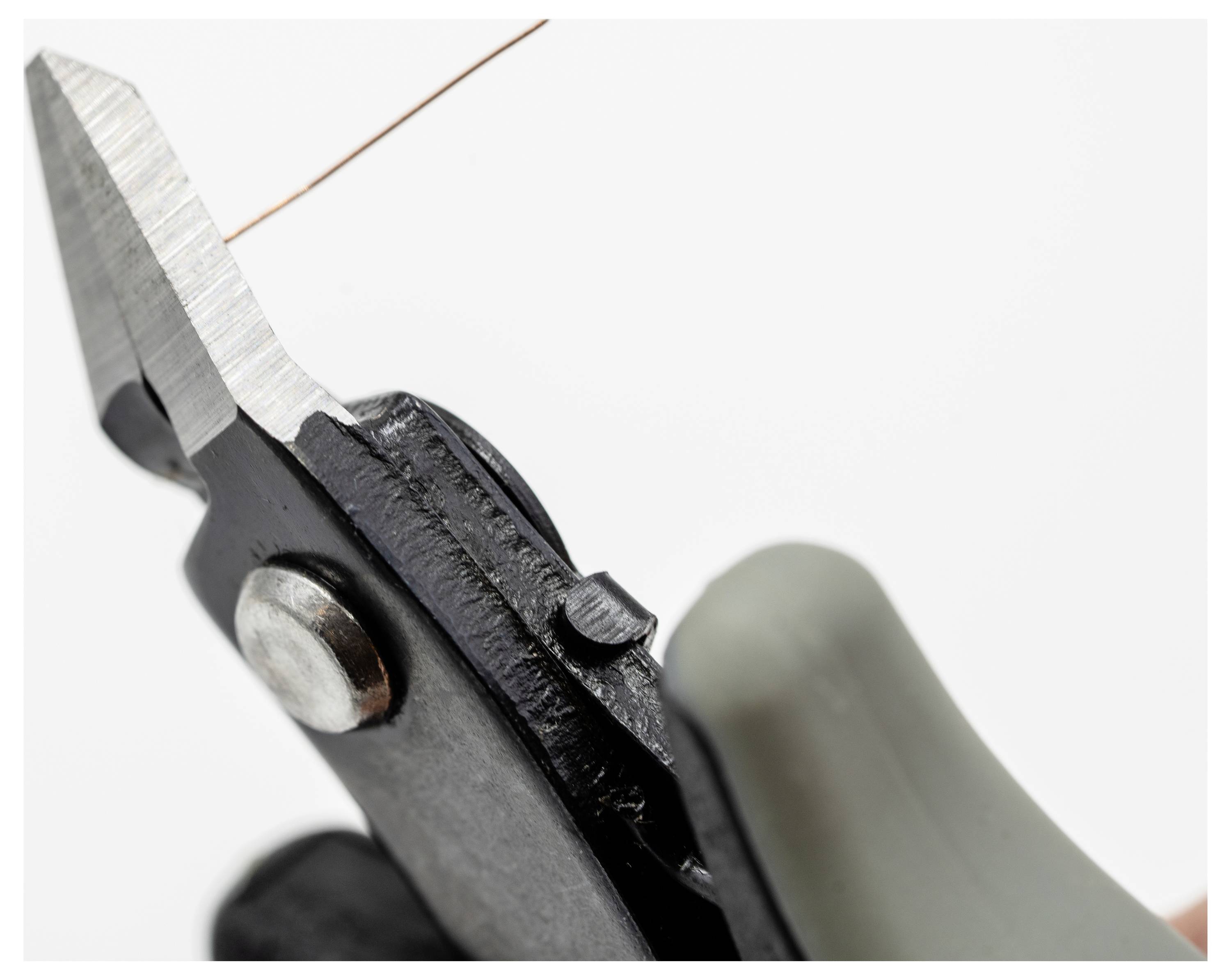 Hand, die Drahtschneider hält und einen dünnen Kupferdraht gegen einen einfachen Hintergrund schneidet.