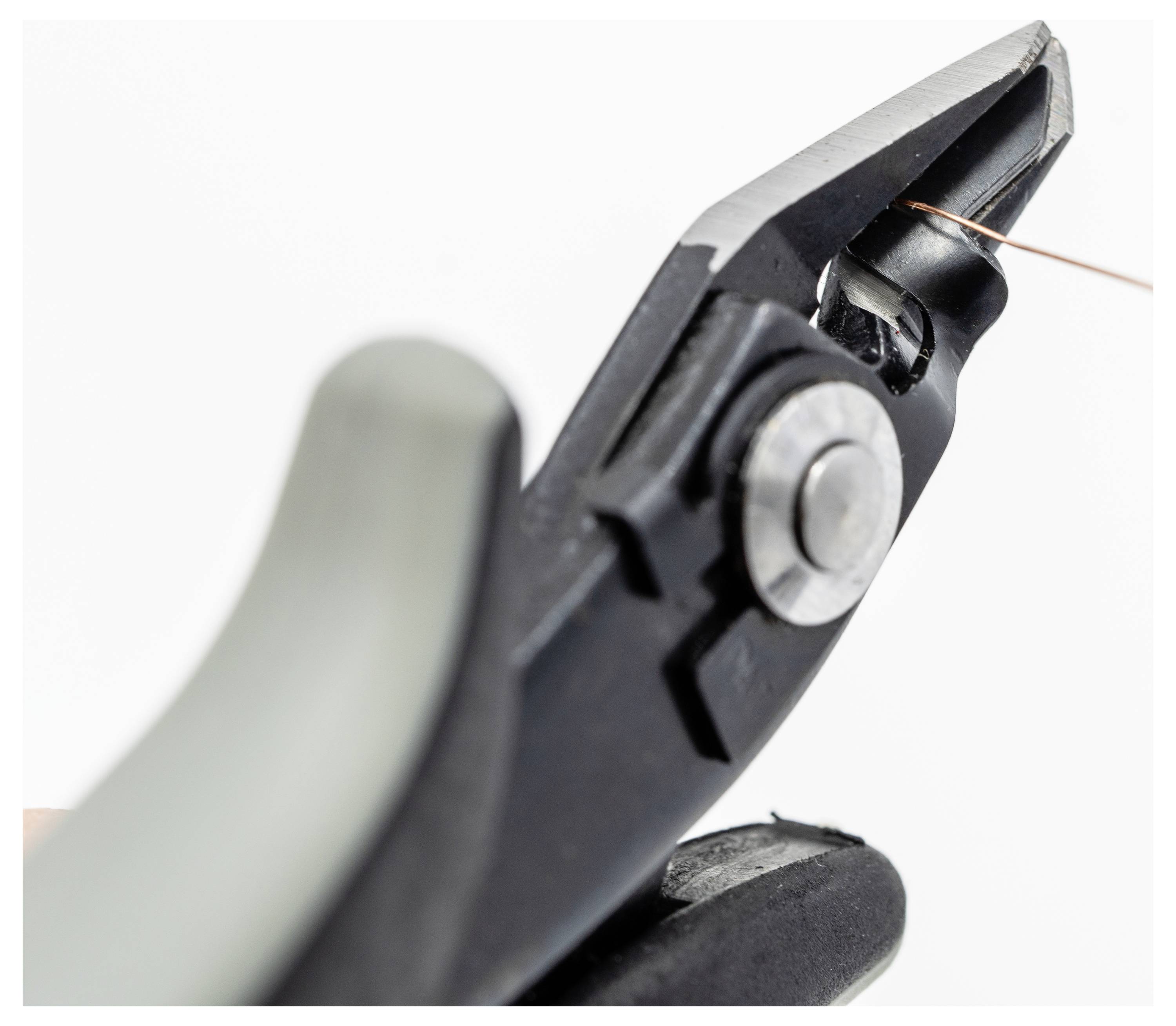 Nahaufnahme der Klingen einer Drahtschere, mit einem dünnen Kupferdraht zwischen ihnen positioniert, bereit zum Schneiden.