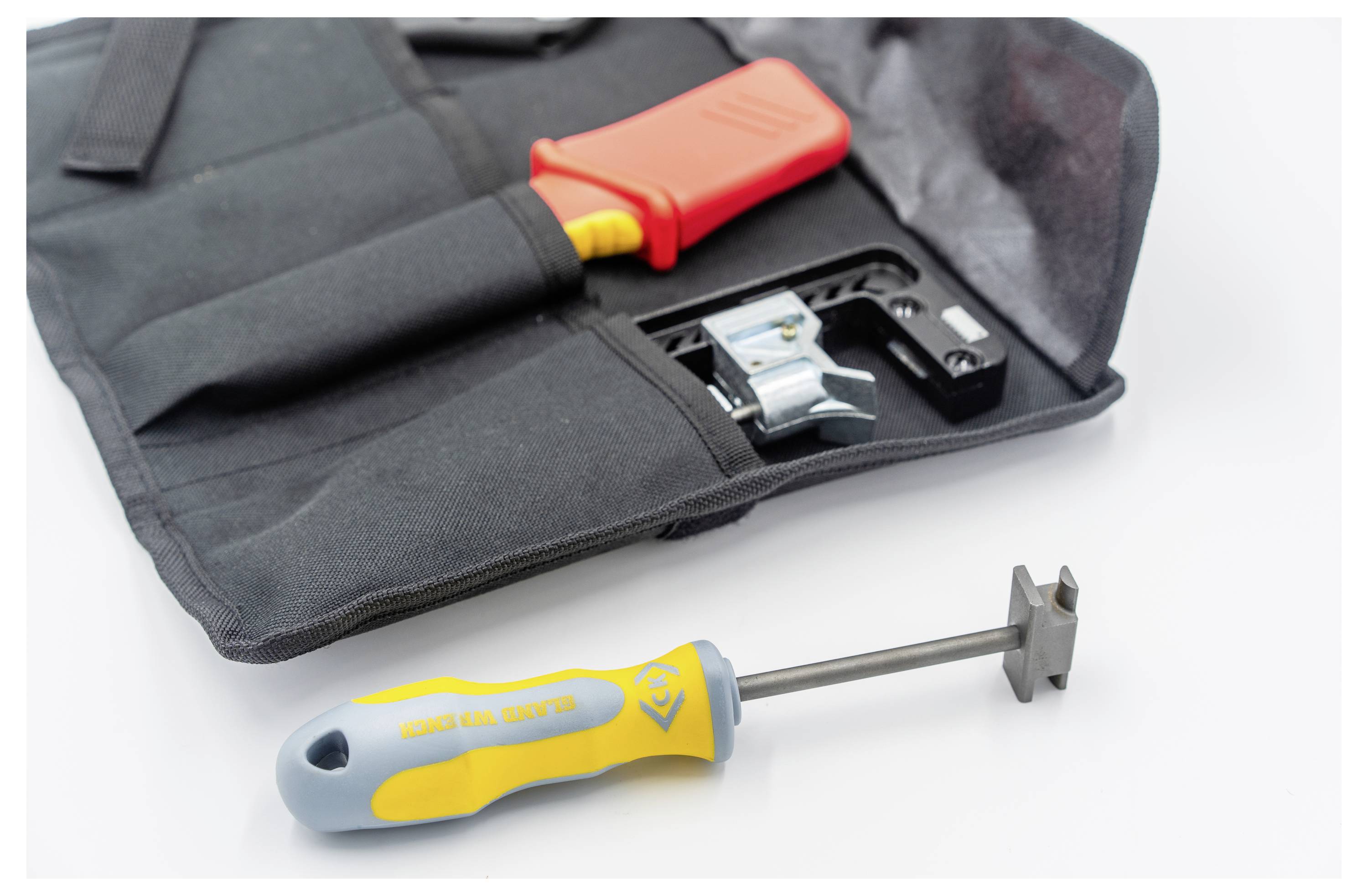 Ein Werkzeugsatz mit einem roten Abisolierwerkzeug für Kabel in einem schwarzen Koffer und einem Werkzeug mit gelbem Griff und Metallende daneben.