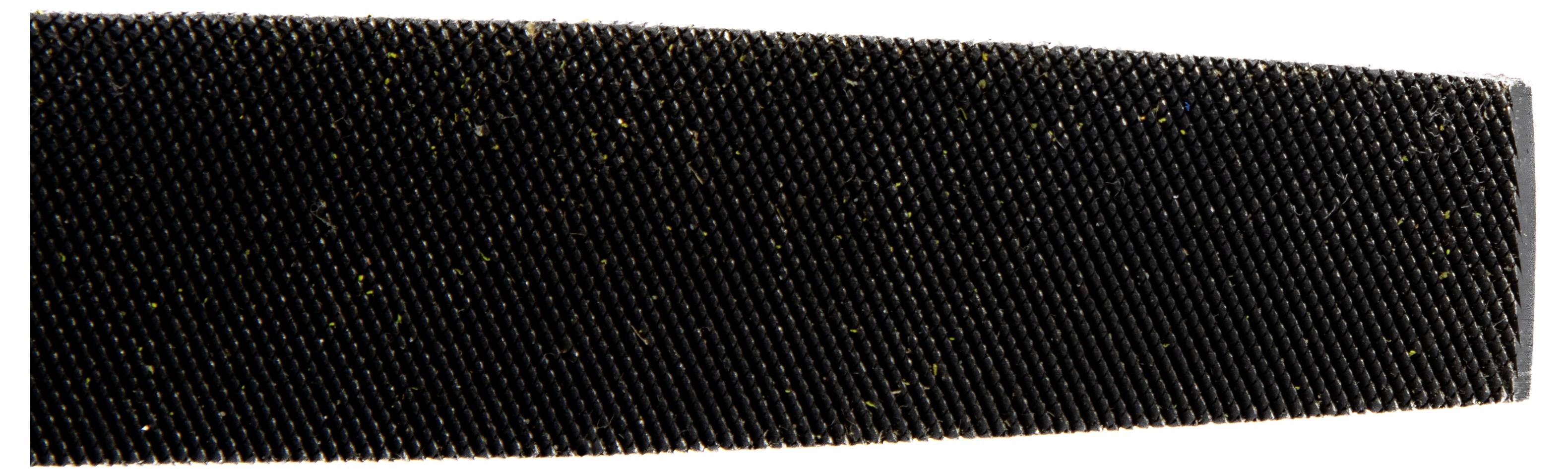 Eine Nahaufnahme einer strukturierten schwarzen Oberfläche, möglicherweise eine grobe Feile oder ein Schleifwerkzeug, die ein detailliertes Muster und Materialfasern zeigt.