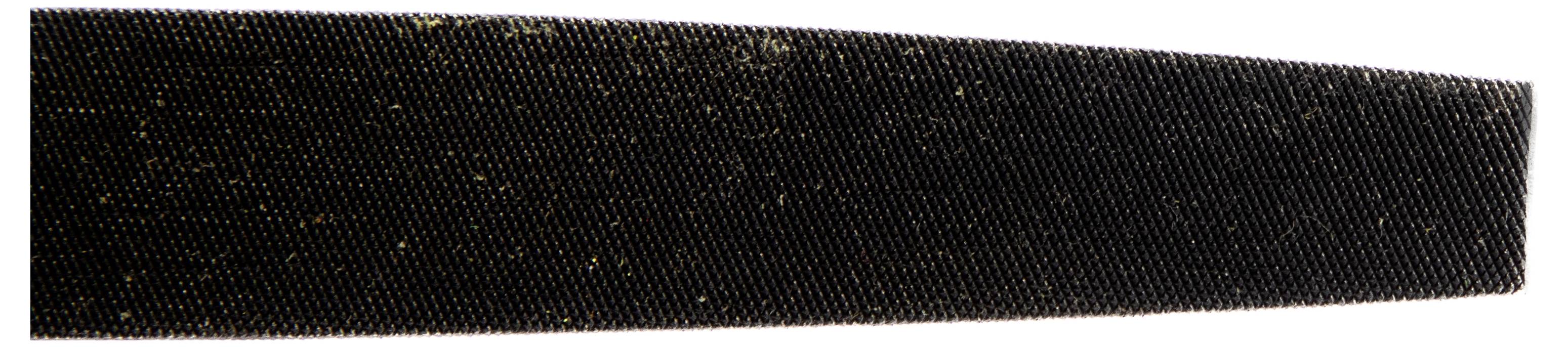 Nahaufnahme eines schwarzen gezahnten Objekts, möglicherweise eine Feile oder ein Werkzeug, das feine horizontale Rillen und Staubkörnchen auf der Oberfläche zeigt.