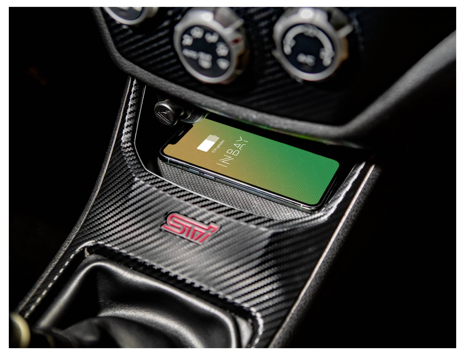 Smartphone lädt sich drahtlos in einer Subaru STI Mittelkonsole mit Kohlefaser-Verkleidung und STI-Abzeichen auf.