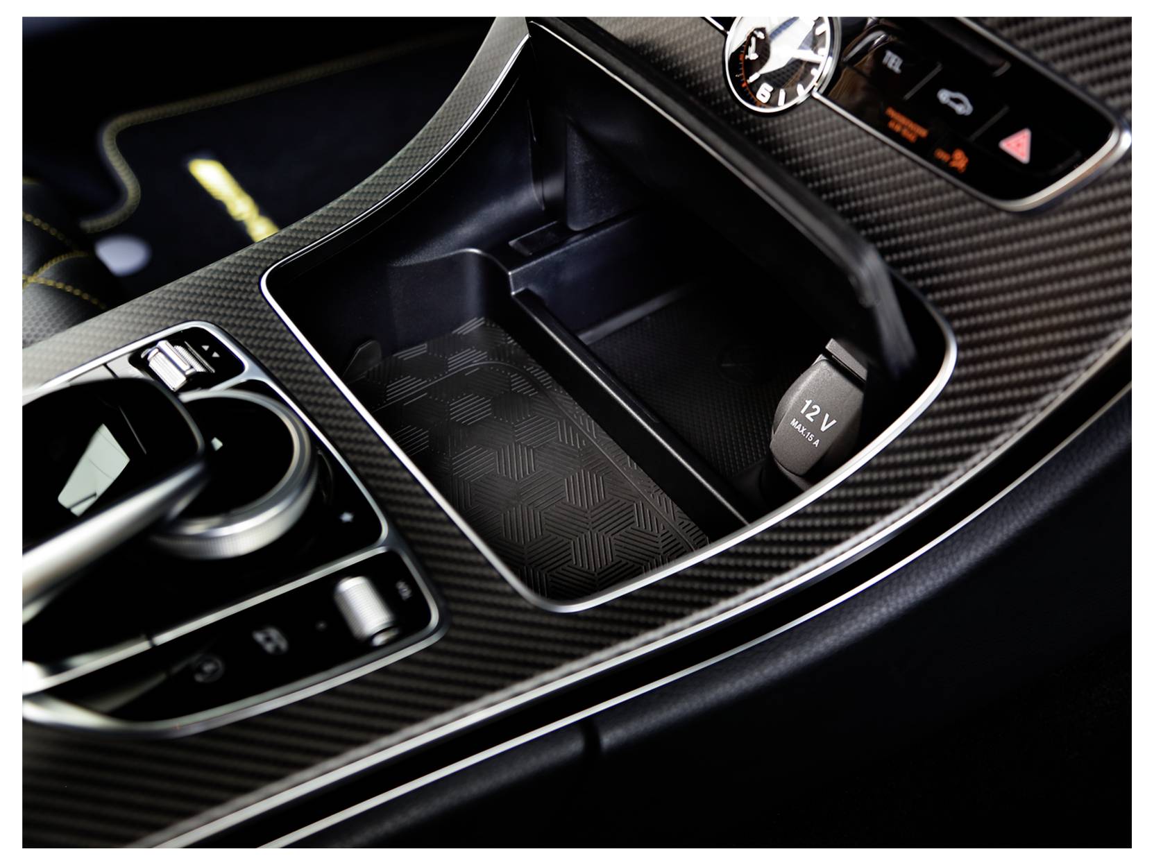Ablage-Tablett in der Mittelkonsole mit 12-V-Stromauslass und Getränkehalter, gezeigt in einer Innenausstattung mit Karbonfaser-Veredelung.