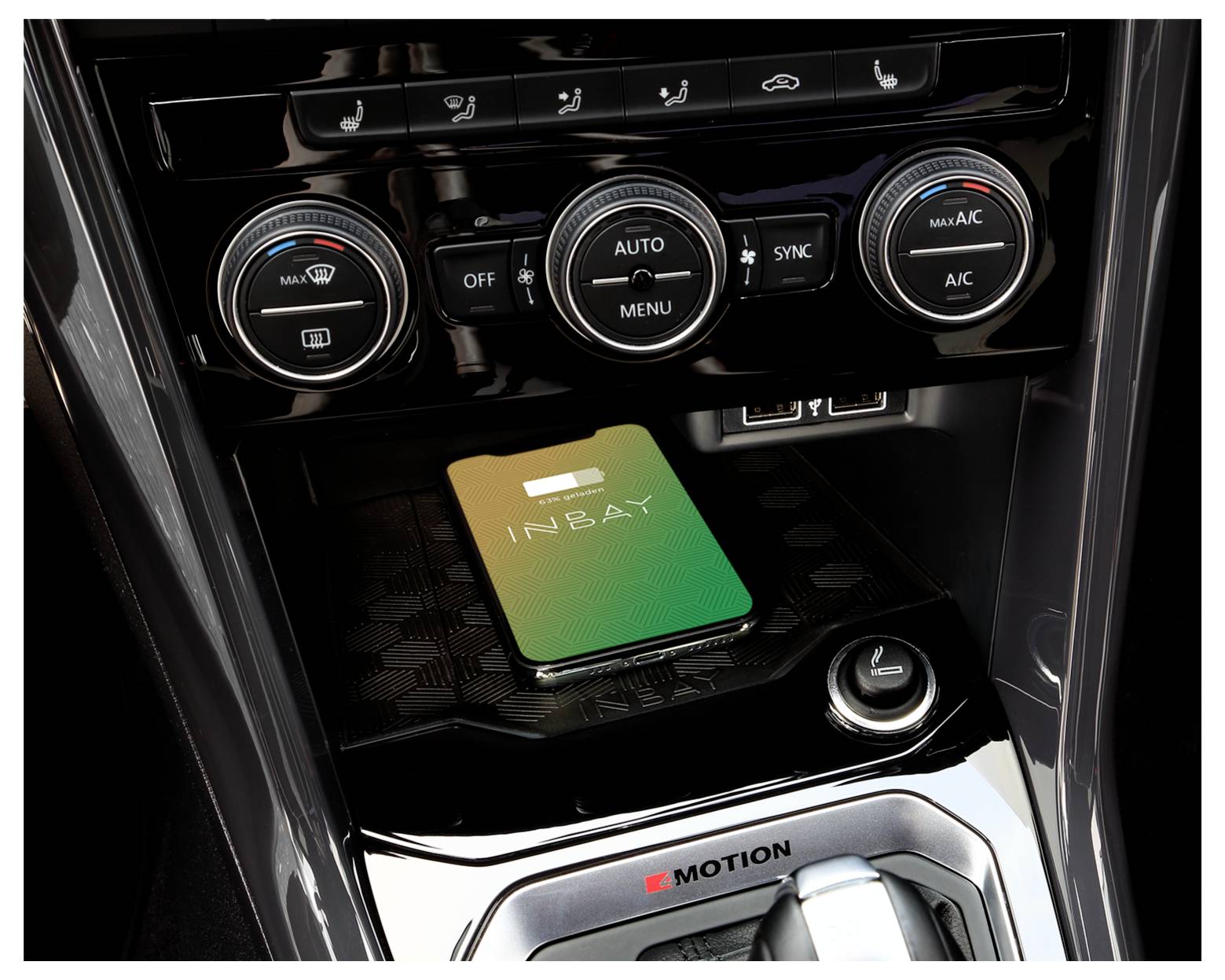 Mittelkonsole eines Fahrzeugs mit Klimareglern über einer grün-goldenen INBAY-Ladeplattform für kabelloses Laden und 