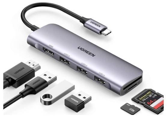 Bild eines UGREEN USB-C-Hubs mit mehreren Anschlüssen, darunter HDMI, USB-A und Kartenleser. Verschiedene Stecker und Speicherkarten in der Nähe abgebildet.