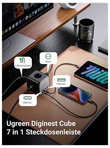 Ein Schreibtisch mit einem Steckdosenwürfel 'Ugreen Diginest Cube 7 in 1' zeigt, wie verschiedene Geräte angeschlossen sind.
