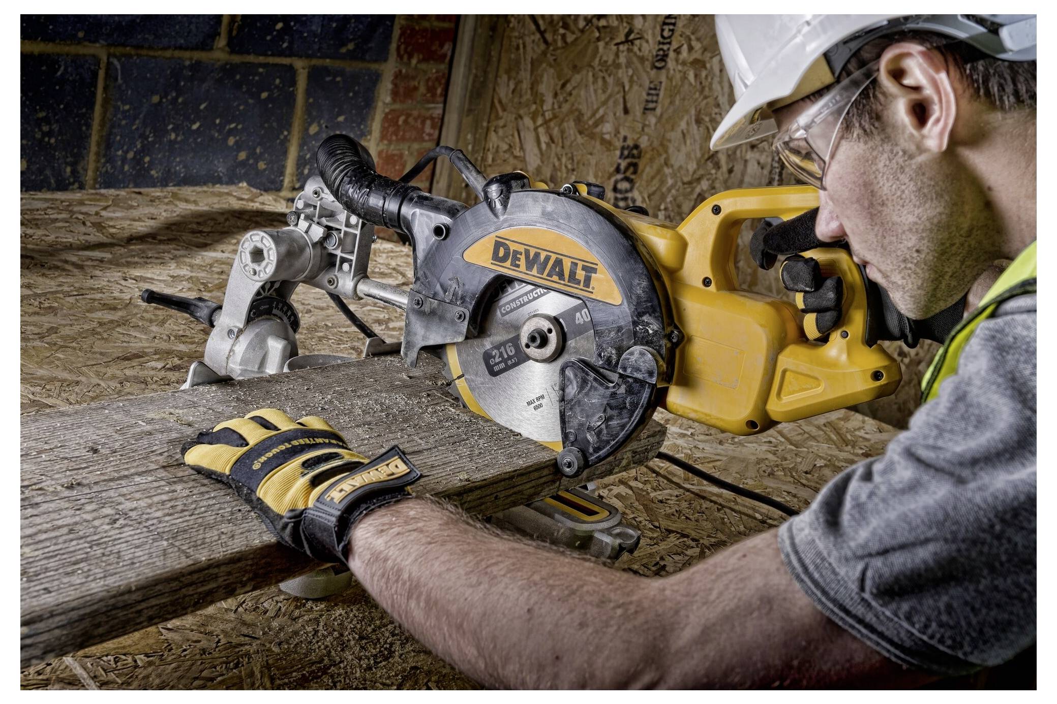 Eine Person trägt Schutzausrüstung, während sie eine DeWalt-Kreissäge bedient und ein Holzbrett in einer Werkstattumgebung schneidet.