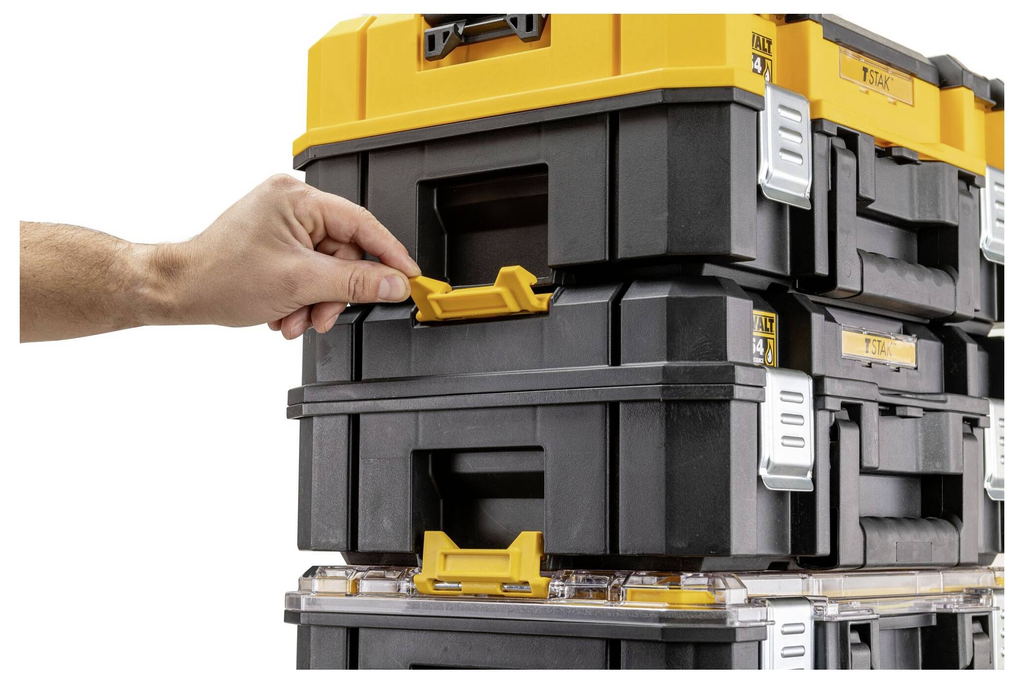 Eine Hand stellt die Verriegelung an einem Stapel von ineinander greifenden schwarzen und gelben Werkzeugkästen ein und betont sichere Lagerung und Organisation.