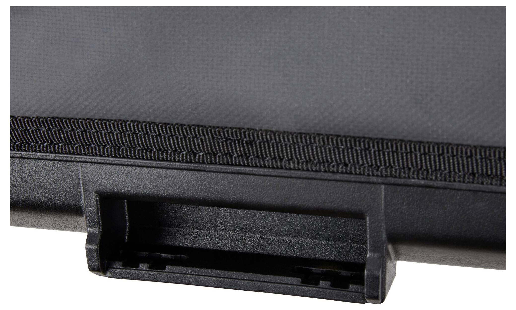 Nahaufnahme eines schwarzen Stoffs oder strukturierten Materials mit einer Kunststoff- oder Gummikante und einem kleinen rechteckigen Griff oder einer Verschlusszunge am unteren Ende.