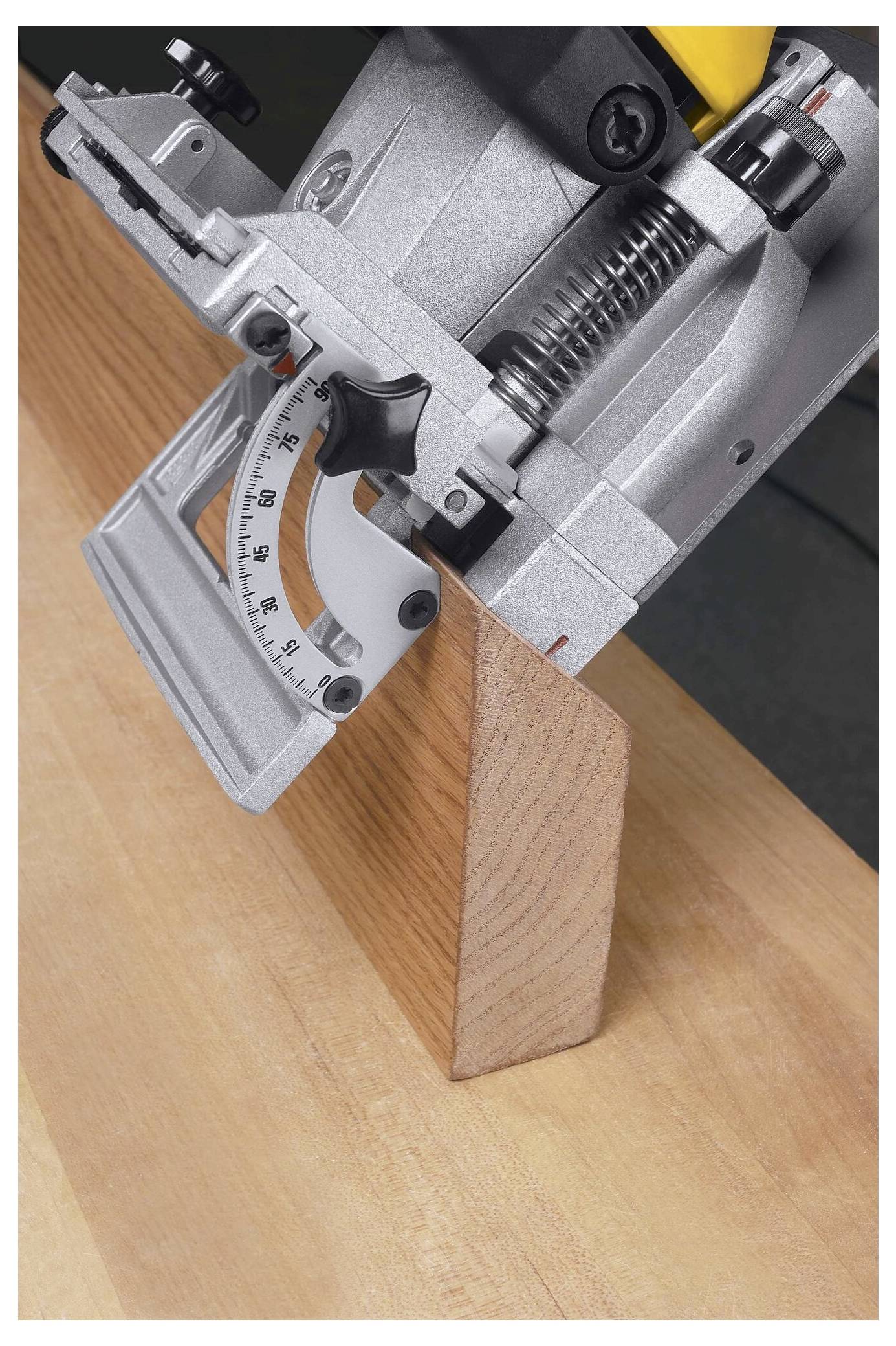 Eine Nahaufnahme eines Holzhobels, der in ein Stück Holz unter einem genauen Winkel schneidet, wobei die Messskala auf dem Werkzeug sichtbar ist.