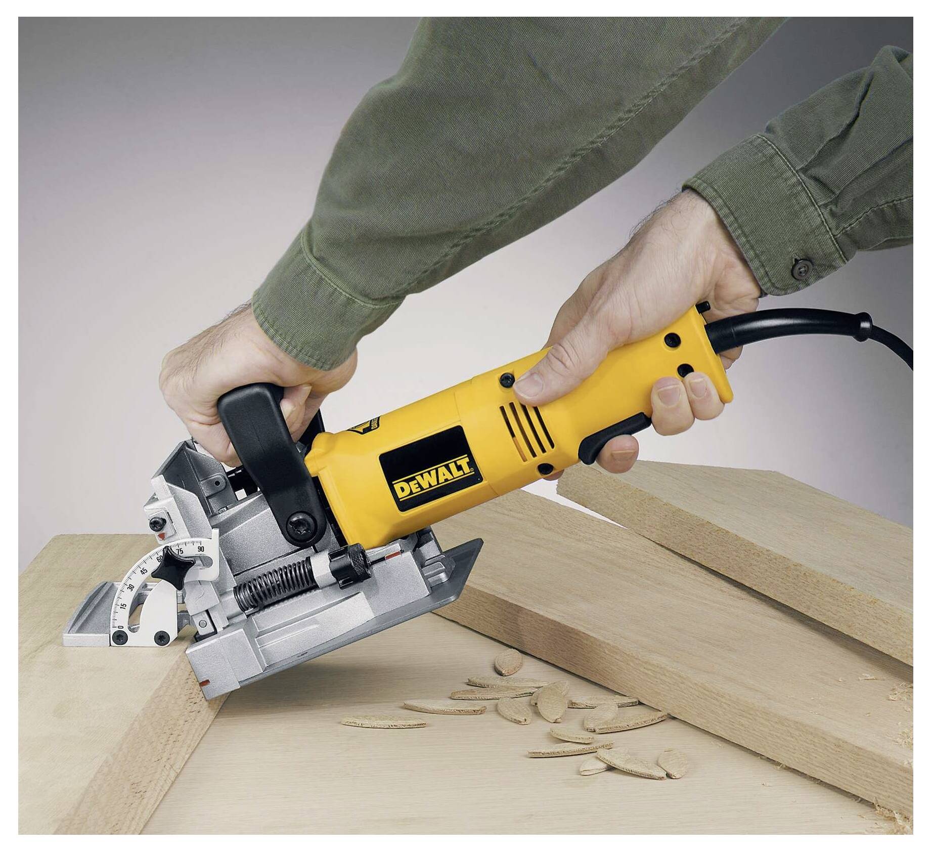 Eine Person verwendet einen gelben Elektroschliff, der Holz in einem Winkel bearbeitet. Holzspäne sind sichtbar und deuten auf aktive Verwendung hin.