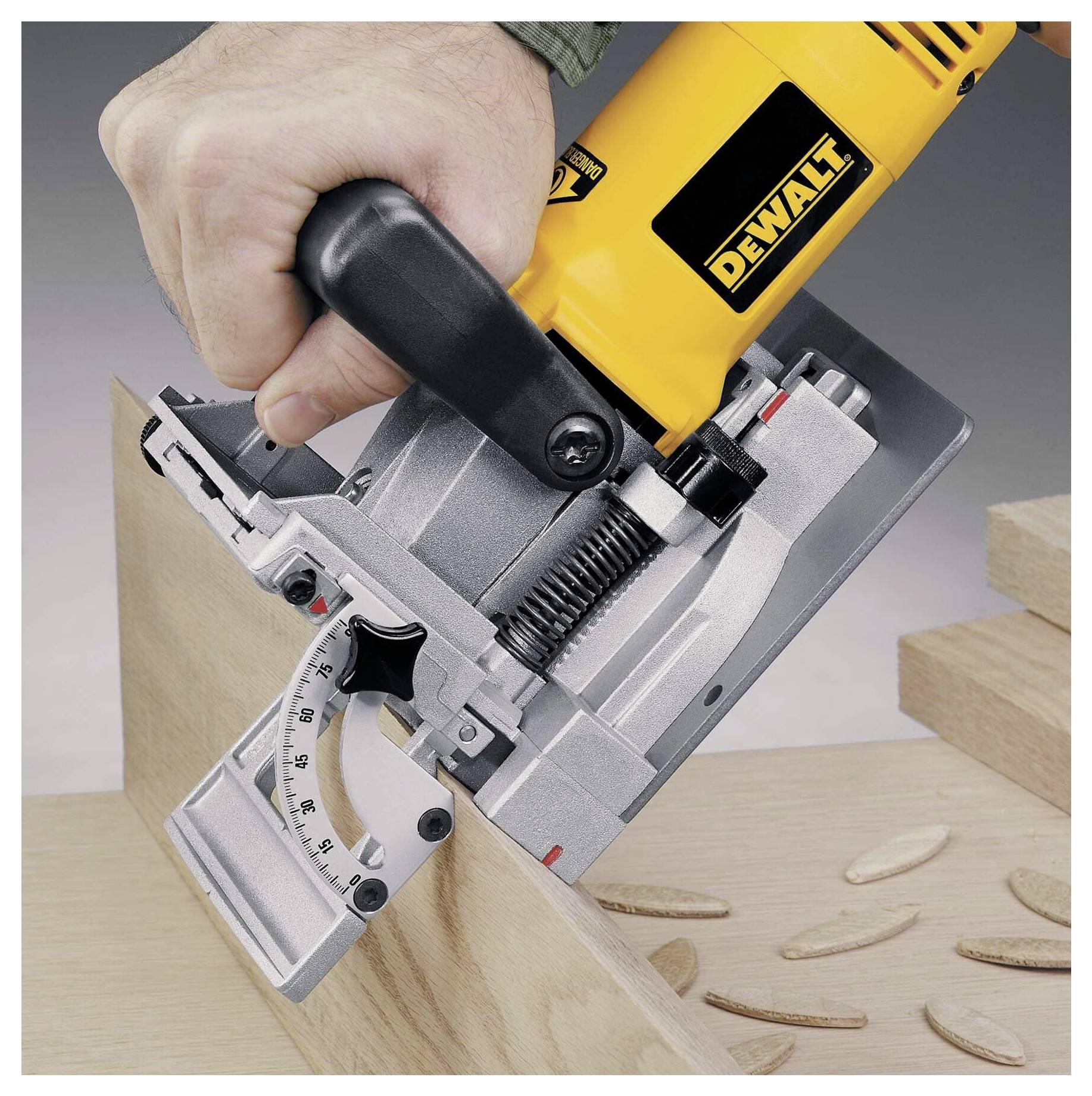 Eine Hand, die eine DEWALT-Biscuitverbindungsmaschine auf einem Holzbrett verwendet, wobei sich Biscuits neben der Maschine befinden und die Holzbearbeitungsmontage andeuten.