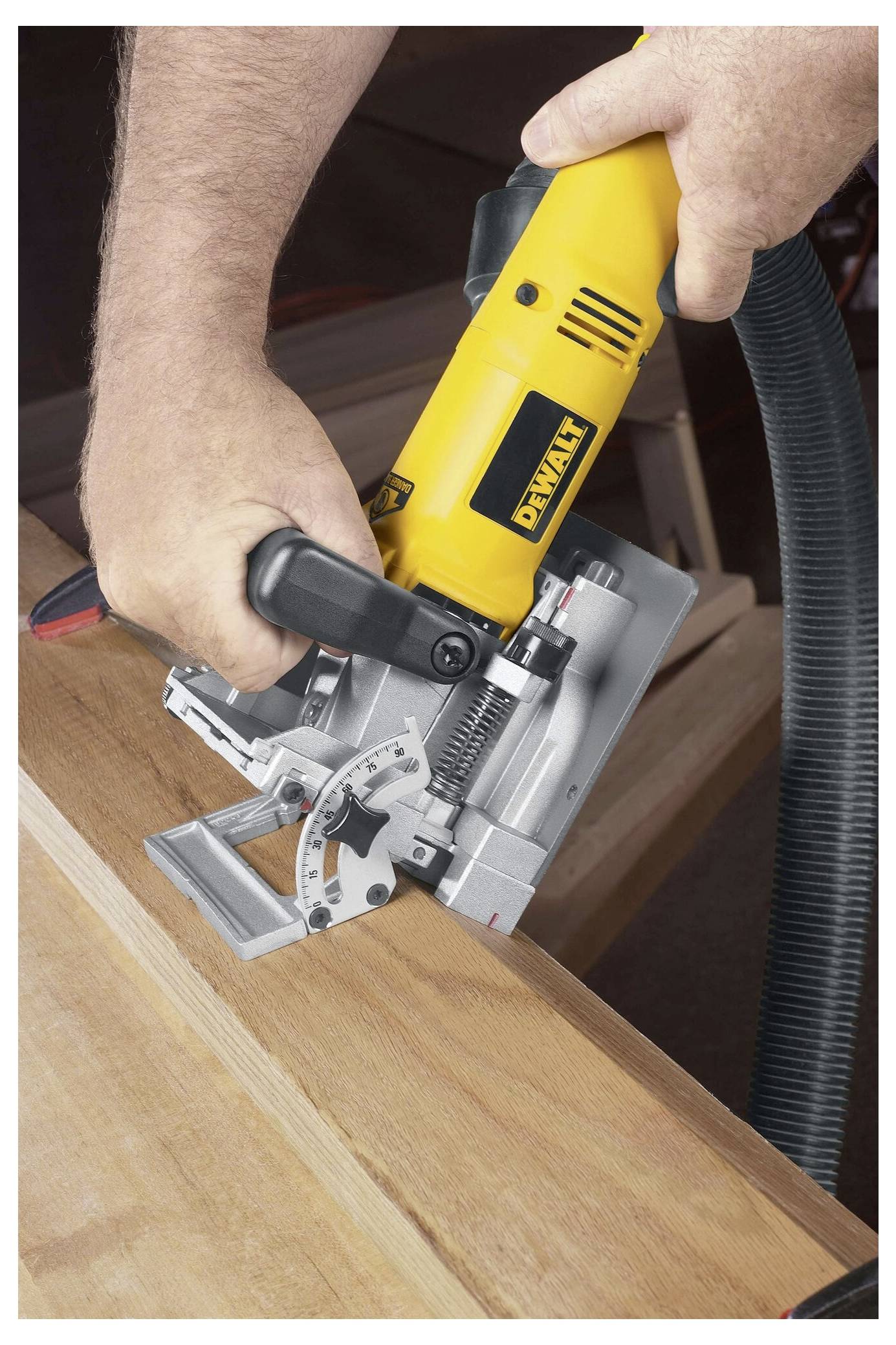 Eine Person bedient ein gelbes Elektrowerkzeug und schneidet präzise Winkel in ein Holzbrett, was auf eine Holzbearbeitung oder Schreinerei hindeutet.