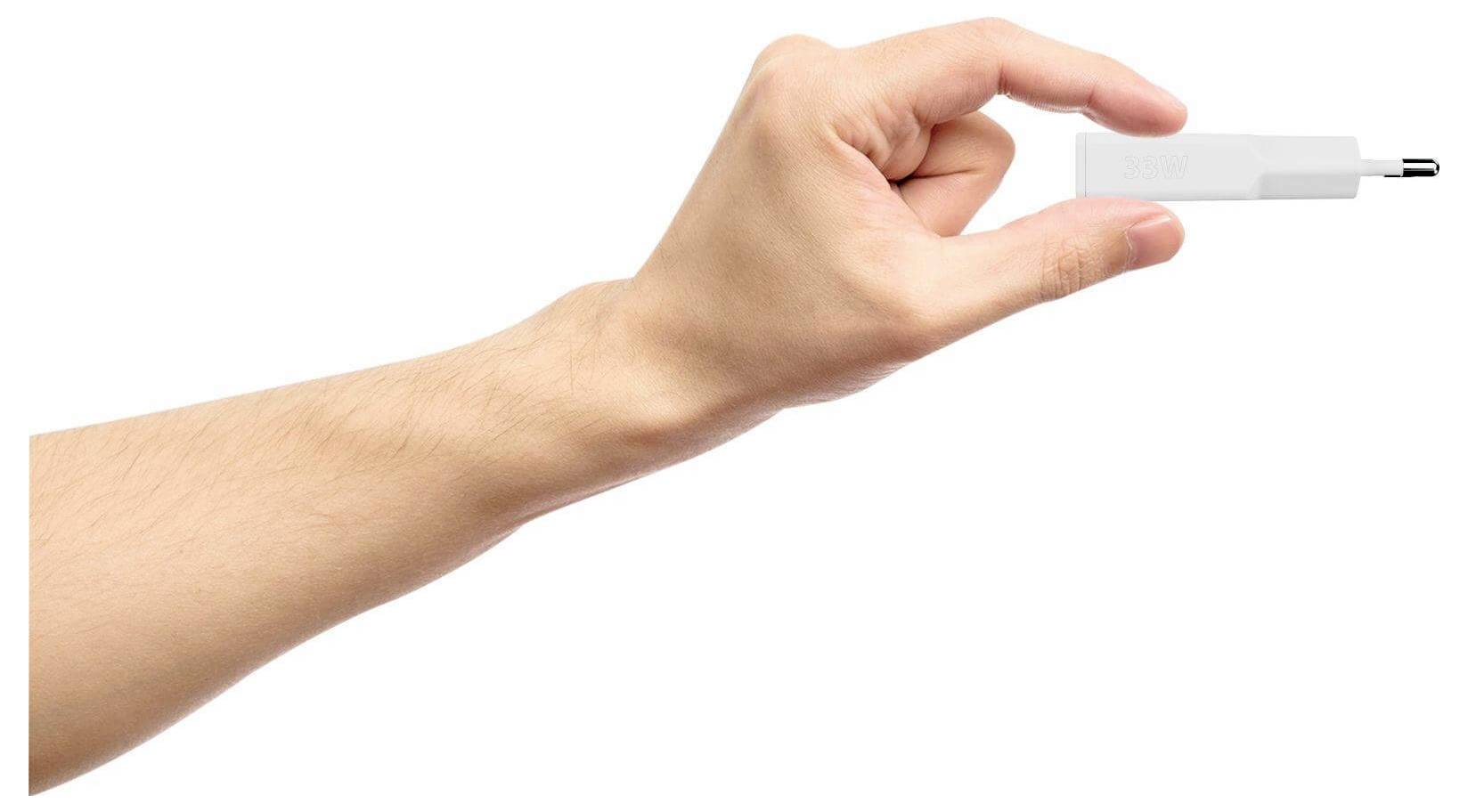 Eine Hand hält ein kleines USB-Laufwerk zwischen Daumen und Zeigefinger vor einem einfachen weißen Hintergrund.